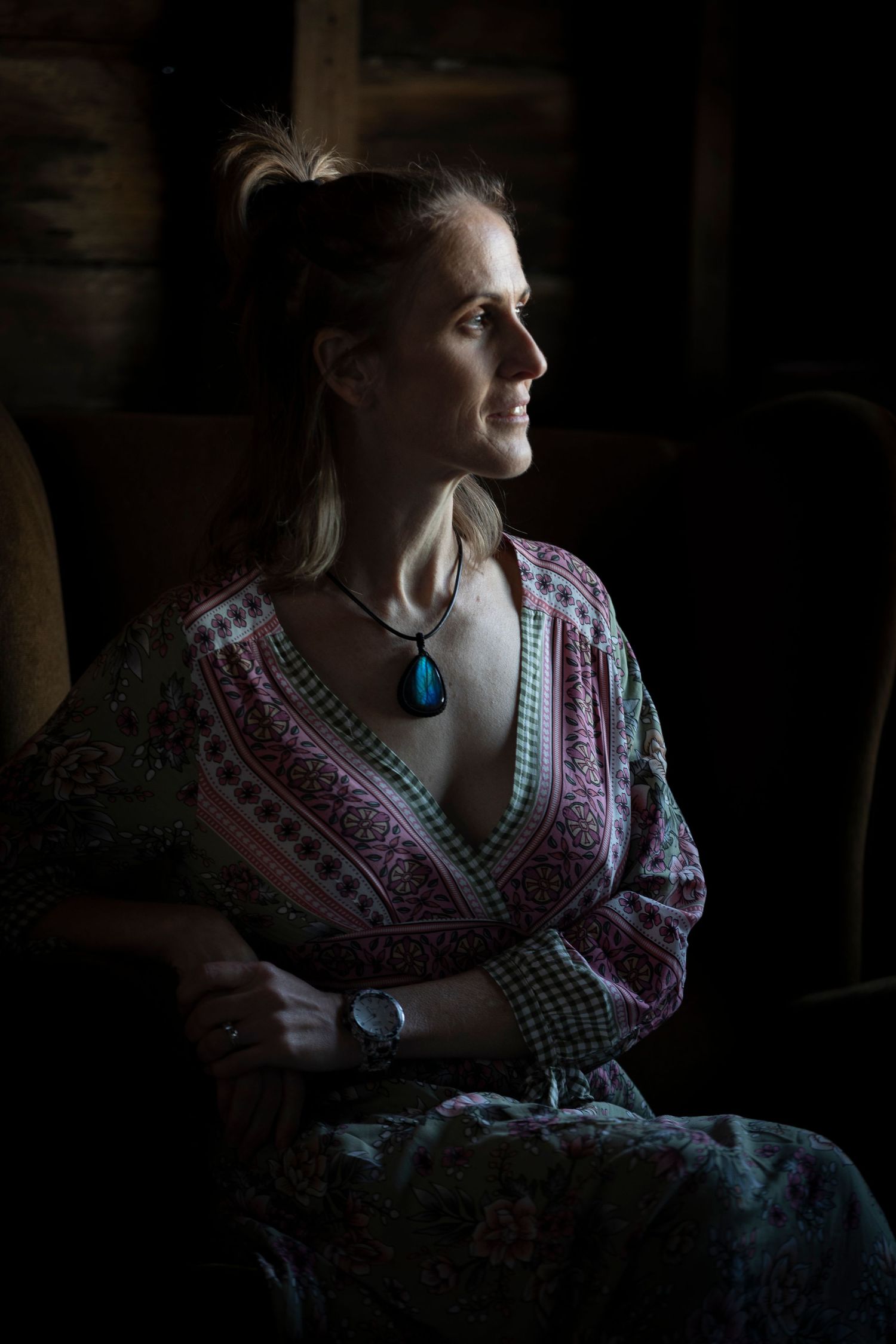 Woman wearing bohemian style dress and turquoise necklace in dramatic side lighting.