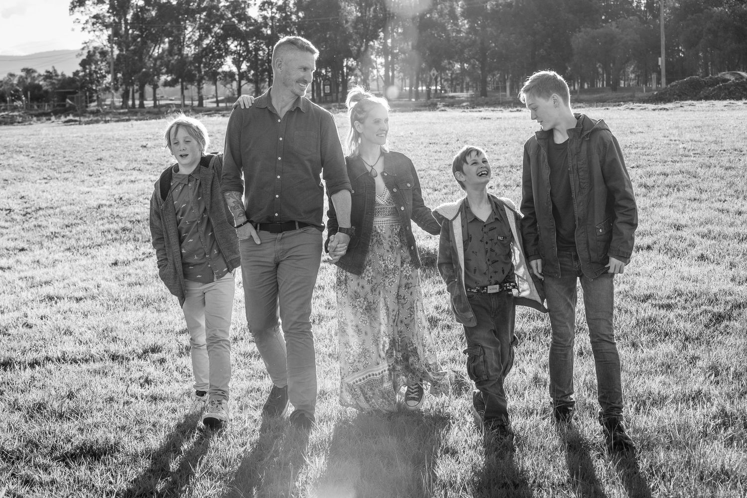 Backlit family group standing together in a sunlit meadow.