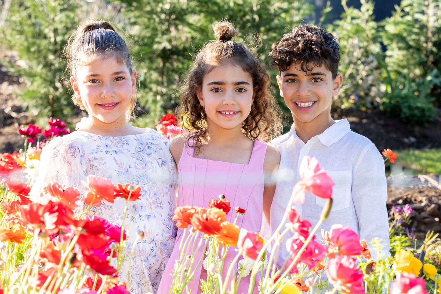 Group photo session in a vibrant garden with colorful flowers and natural outdoor lighting.