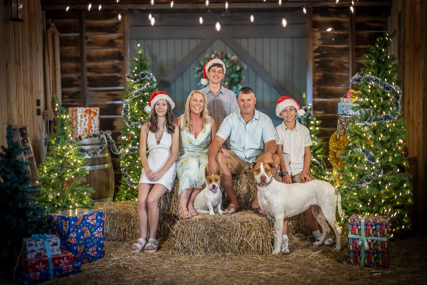 A group sits on rustic wooden steps decorated with holiday decor and festive lights for a seasonal photo.