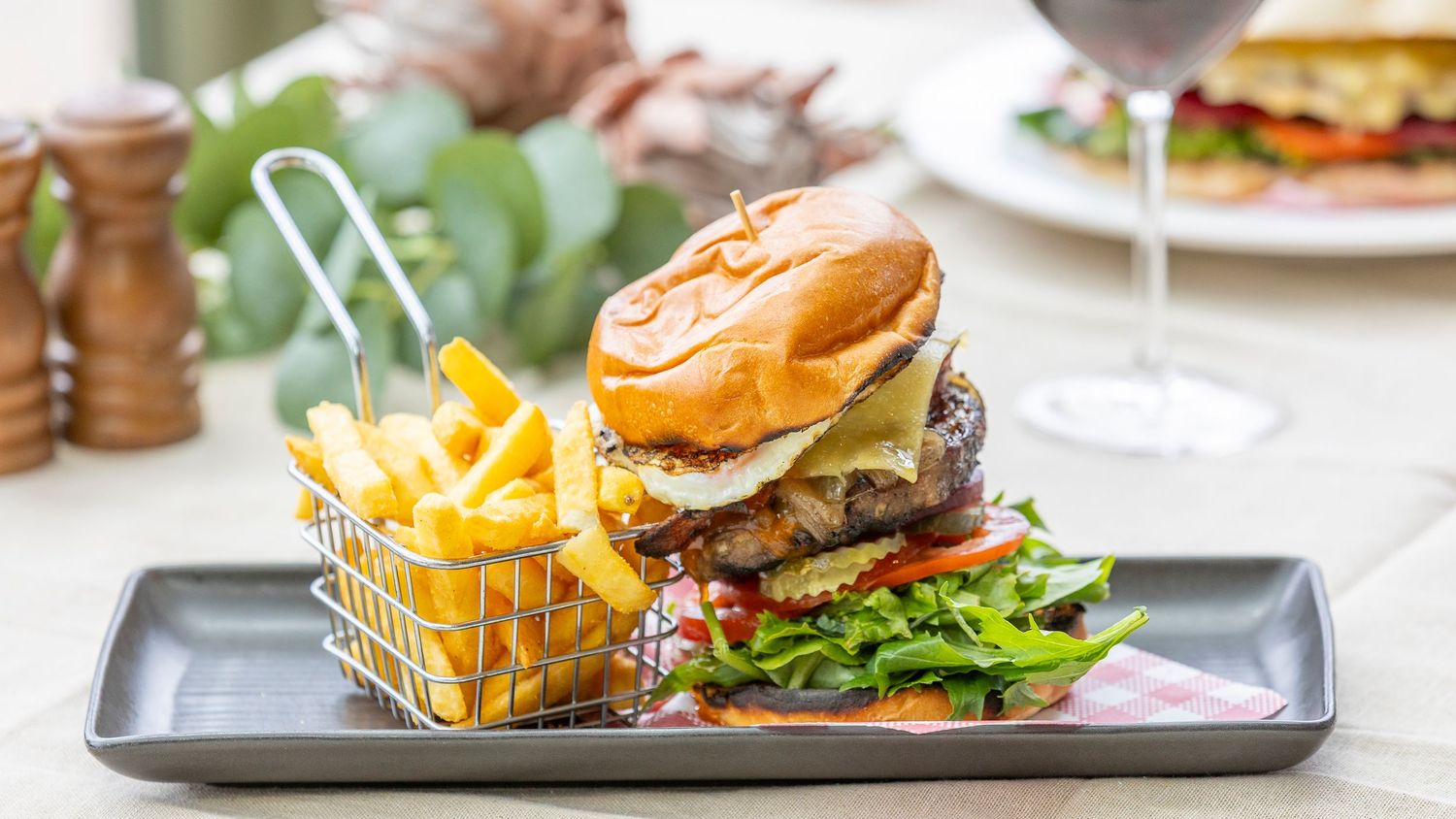 Gourmet burger and fries plated on a wooden serving board in an upscale restaurant setting.