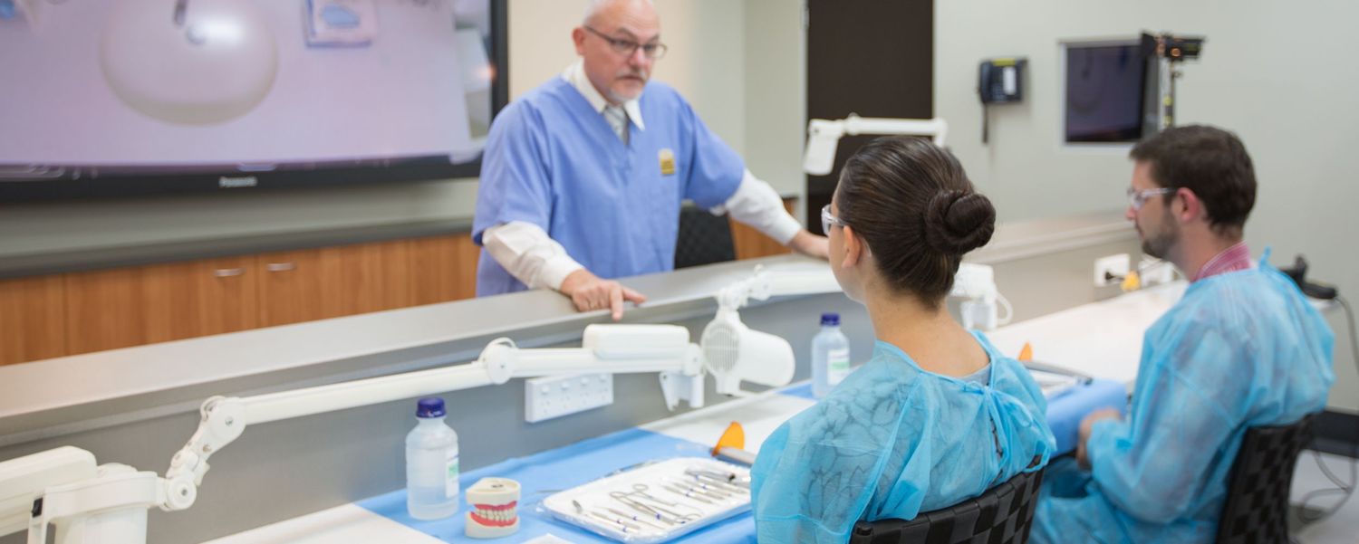 Healthcare professionals in blue scrubs collaborate around a workstation in a medical facility.