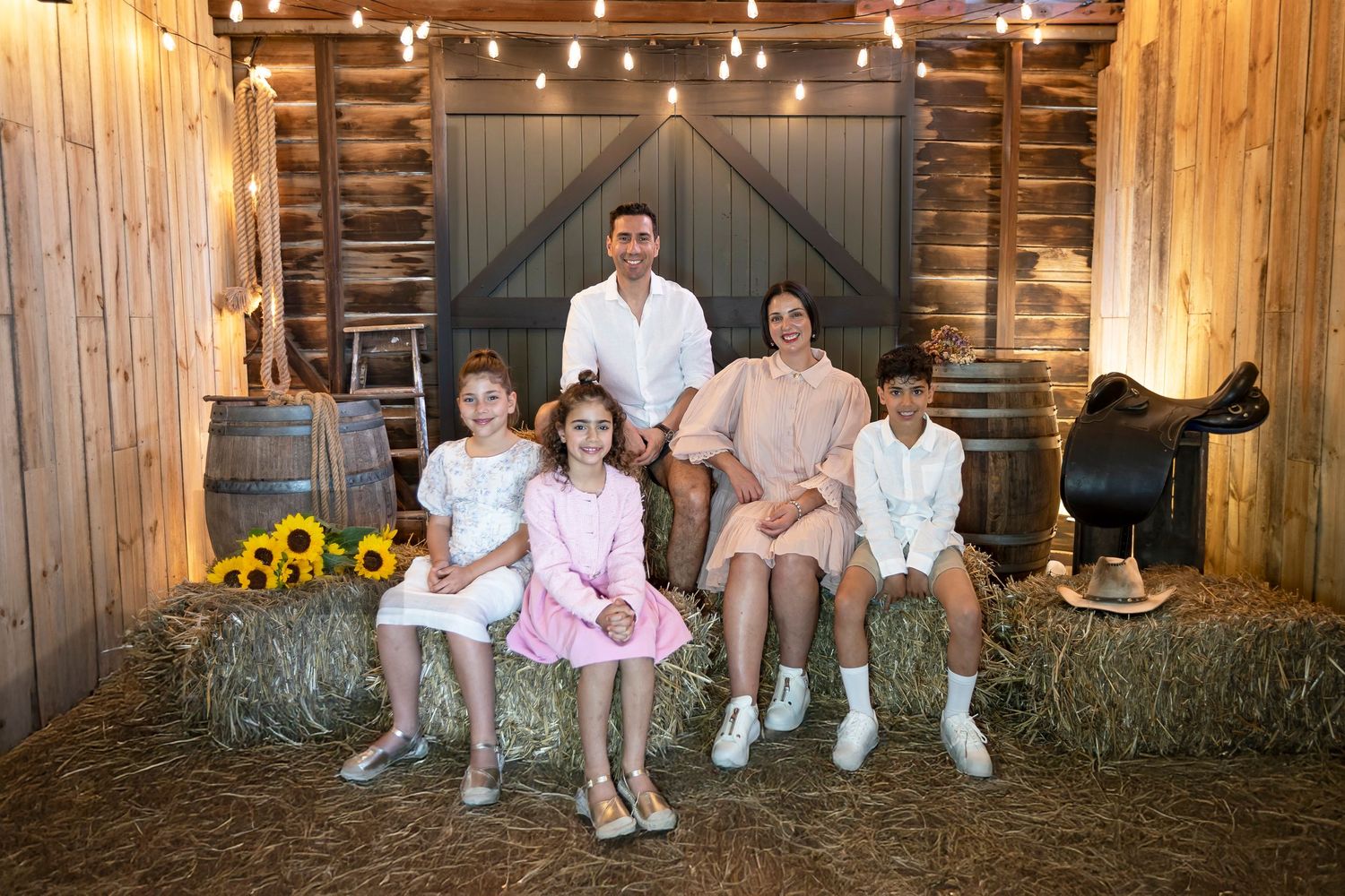 Family portrait session in a rustic barn setting with warm lighting and wooden backdrop.