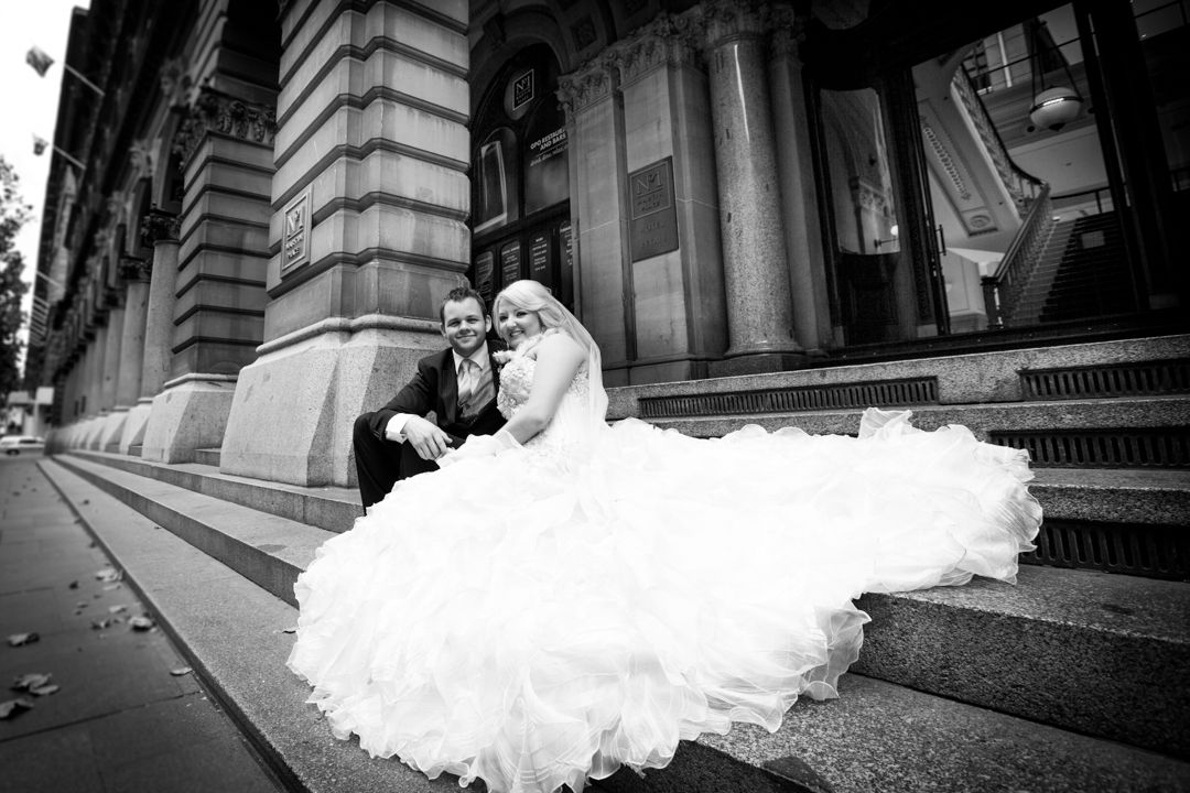 A dramatic black and white wedding photo series showing a flowing white dress in motion against architectural columns.