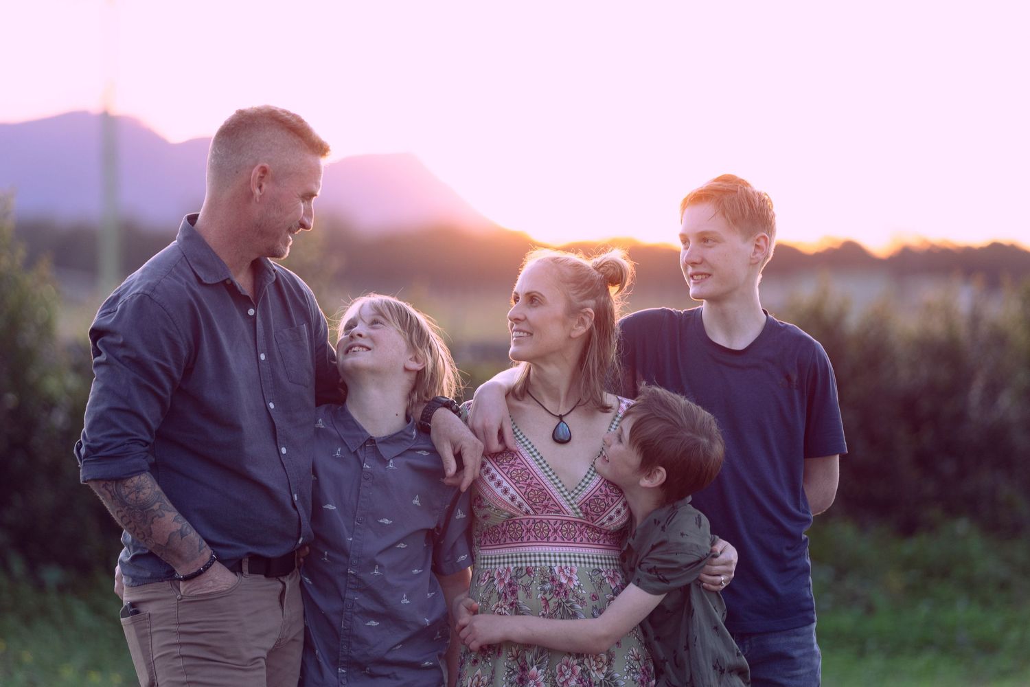 Family gathering at sunset in a rural field with warm lighting.