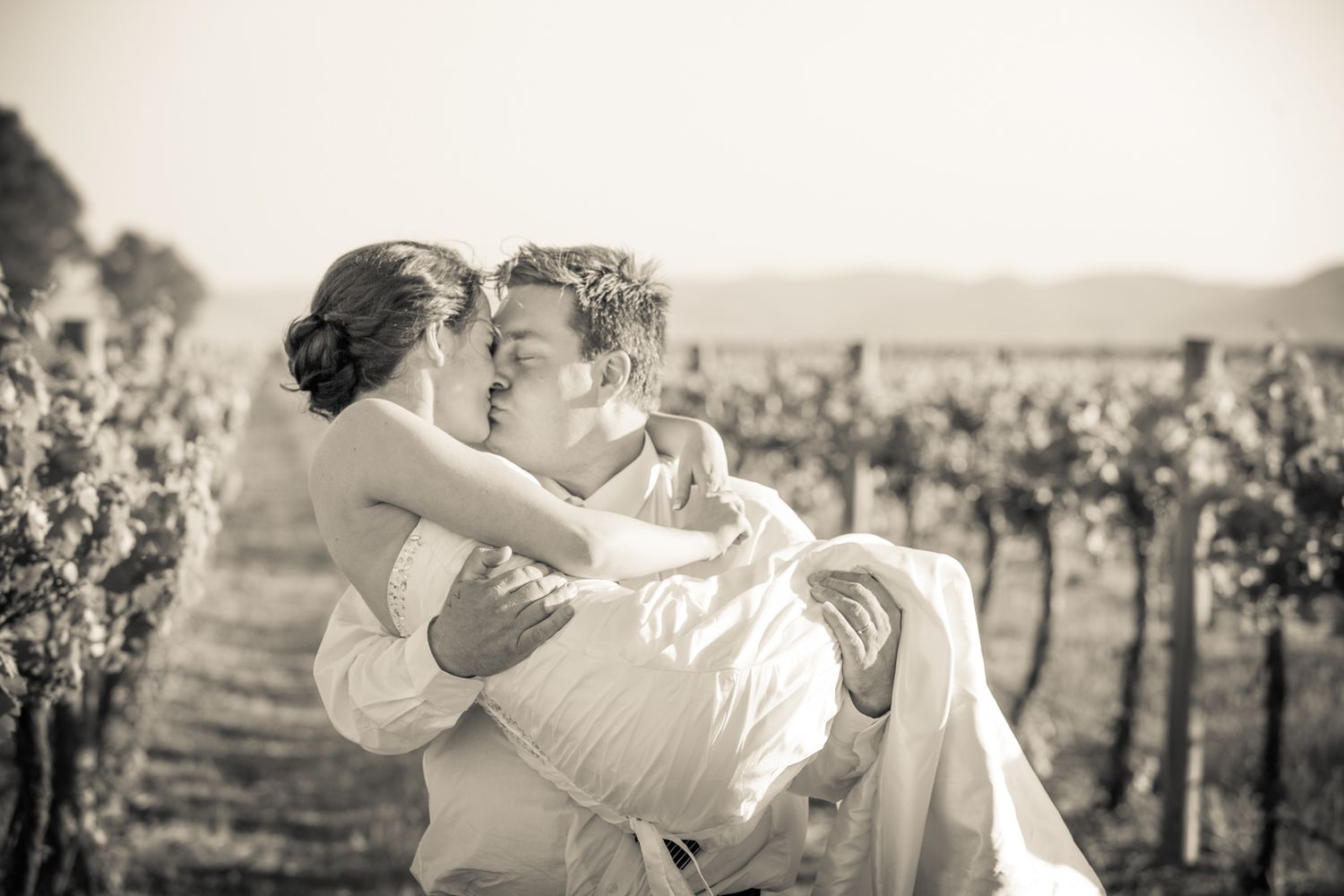 A collection of black and white wedding photos showing romantic moments between couples at a vineyard setting.