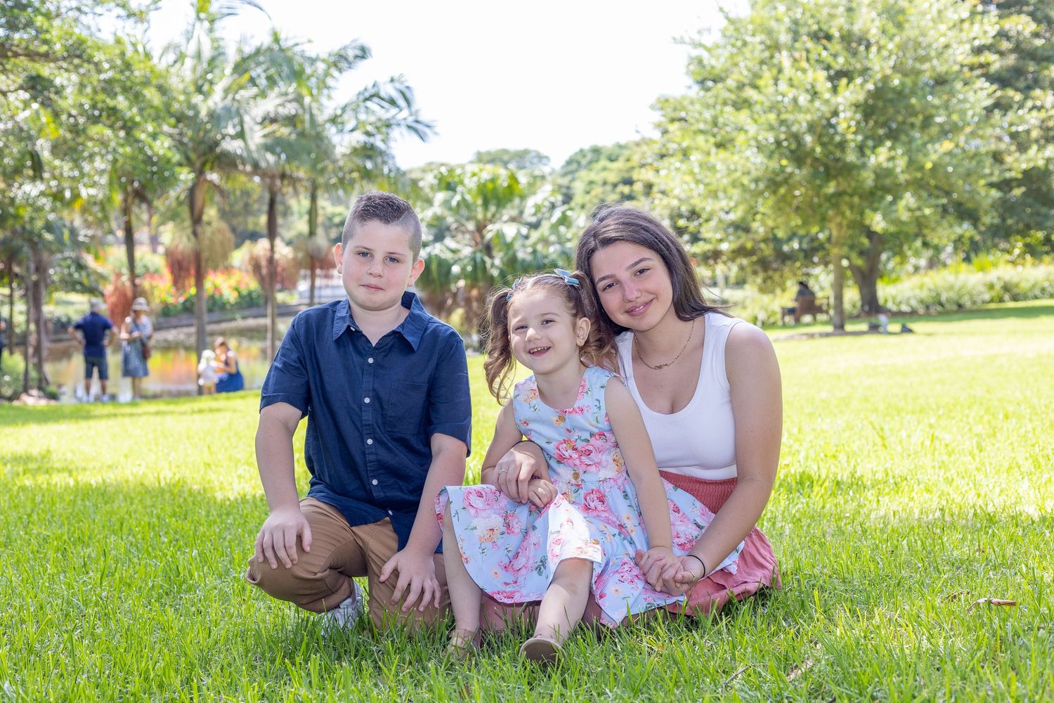 Family lying together on green grass in a sunny park during outdoor photo session.