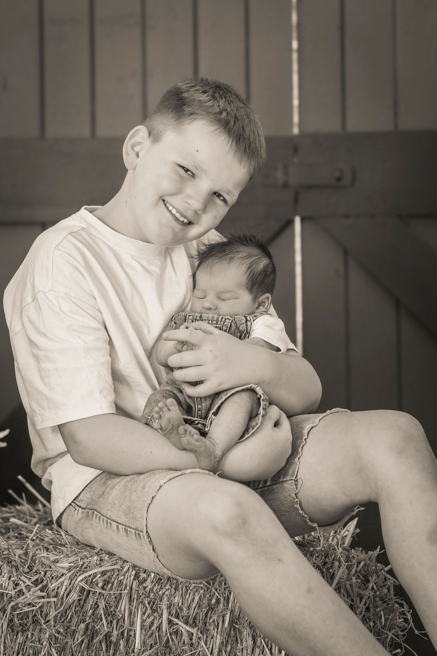 A heartwarming series of black and white photos showing a young child cuddling with a small puppy on hay bales.