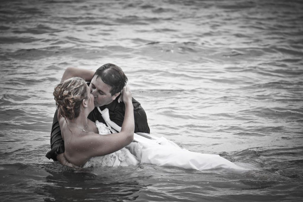 A couple embraces in the water for an artistic black and white romantic trash the dress wedding photo session.