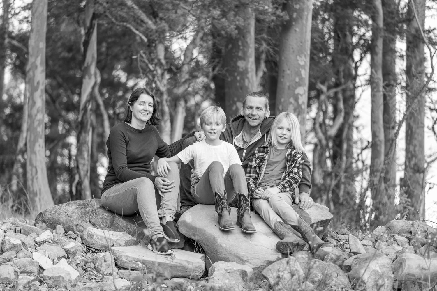 People lounging casually among trees in a scenic wooded area.