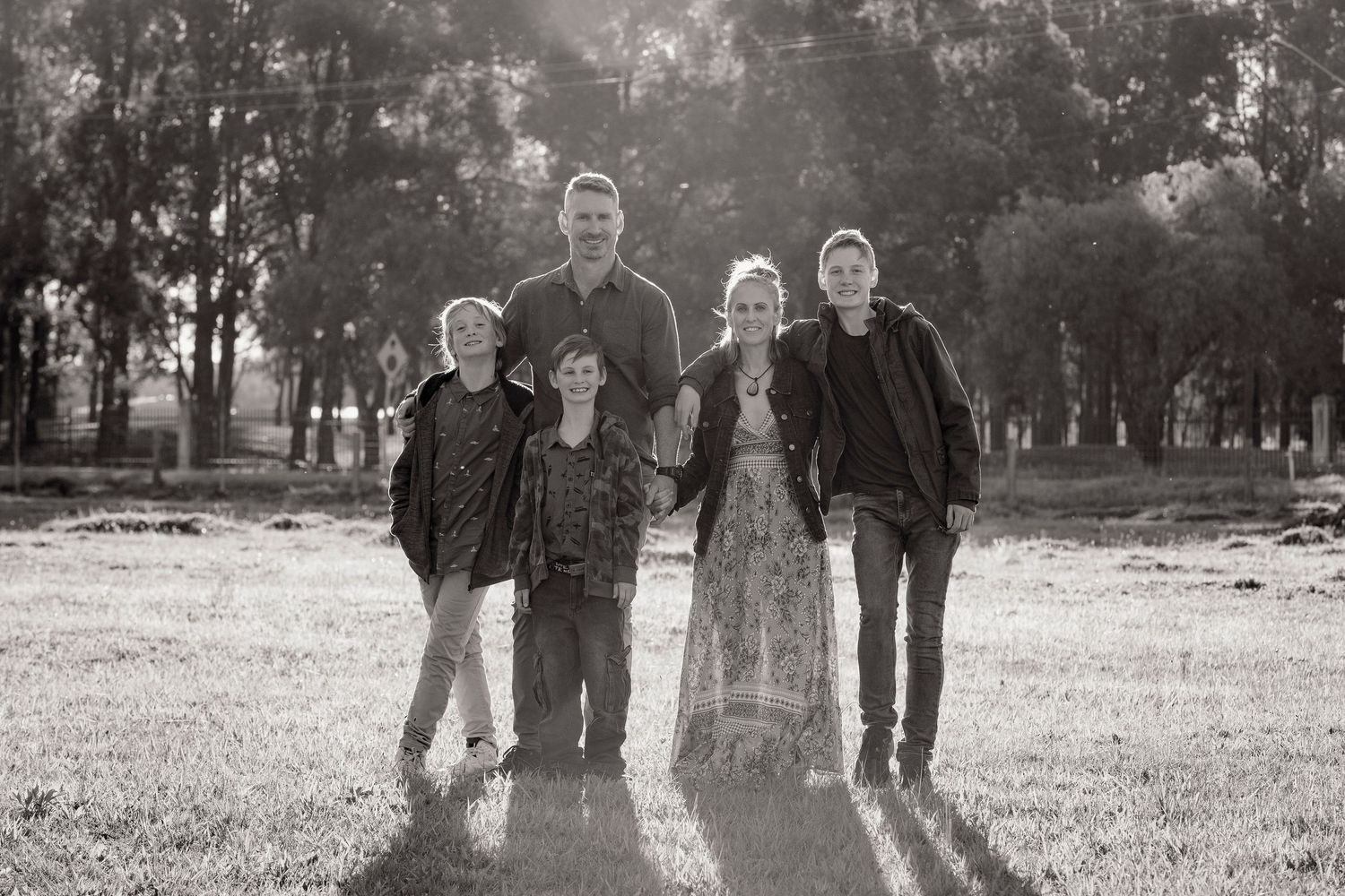 Silhouette of family standing together in a grassy field at sunset.