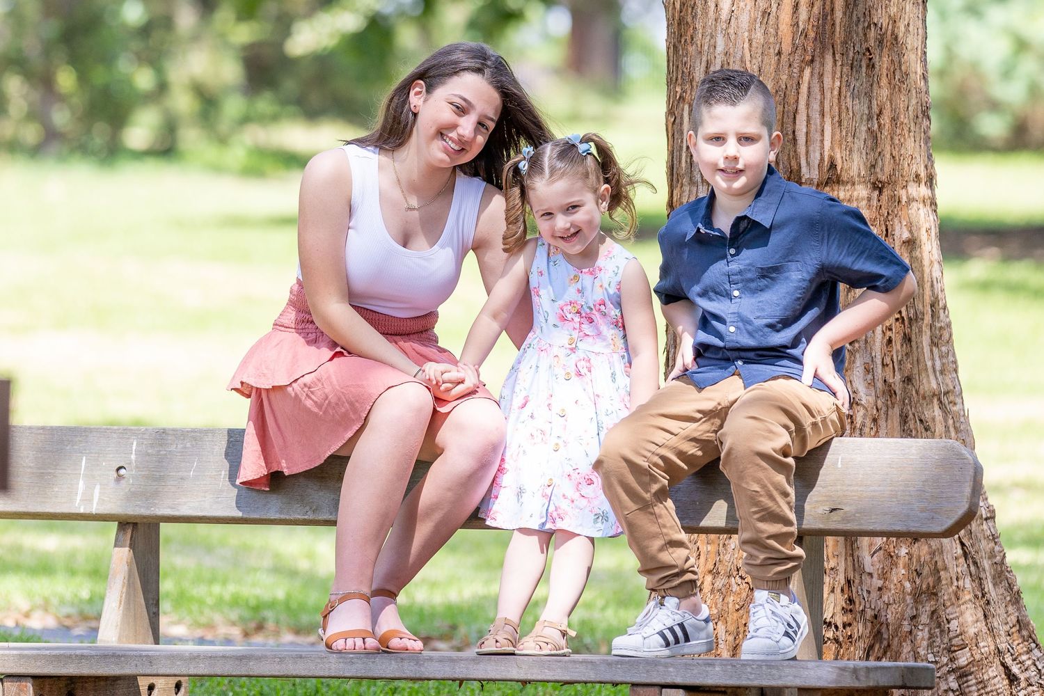 Group enjoys a summer picnic gathering under a shady tree in the park on a sunny afternoon.