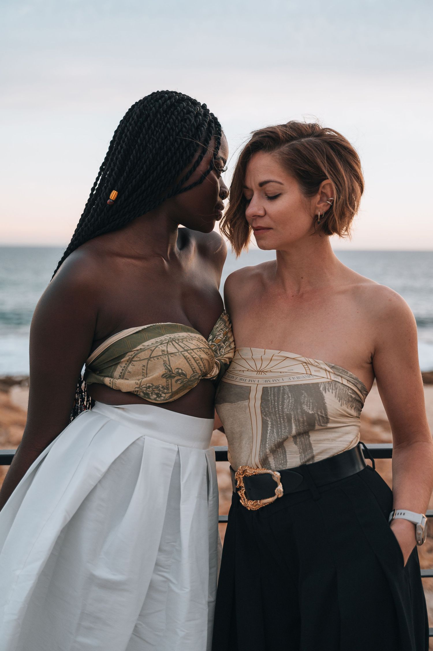 Intimate beach portrait of two people in elegant black and white attire at sunset.