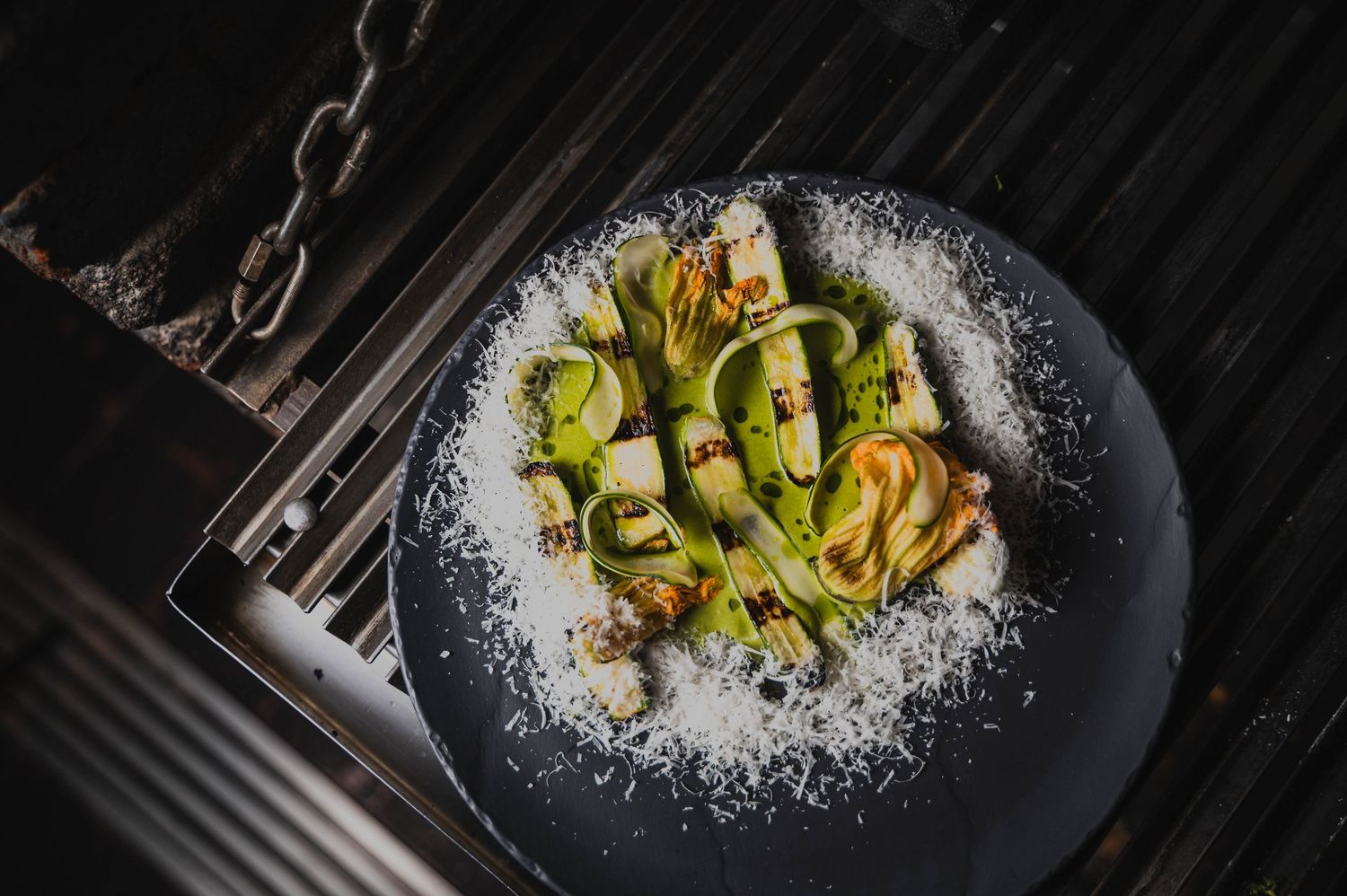 Fresh vegetables plated on black dishes with white garnish.