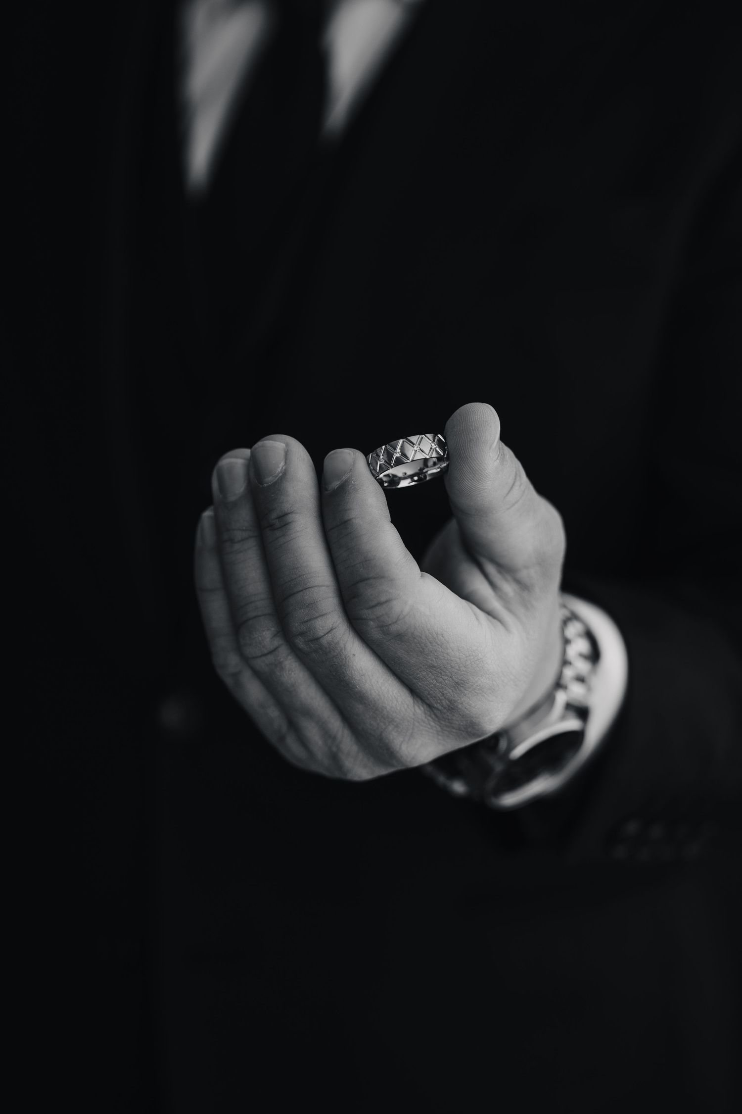 A hand holding an engagement ring captured in dramatic black and white.
