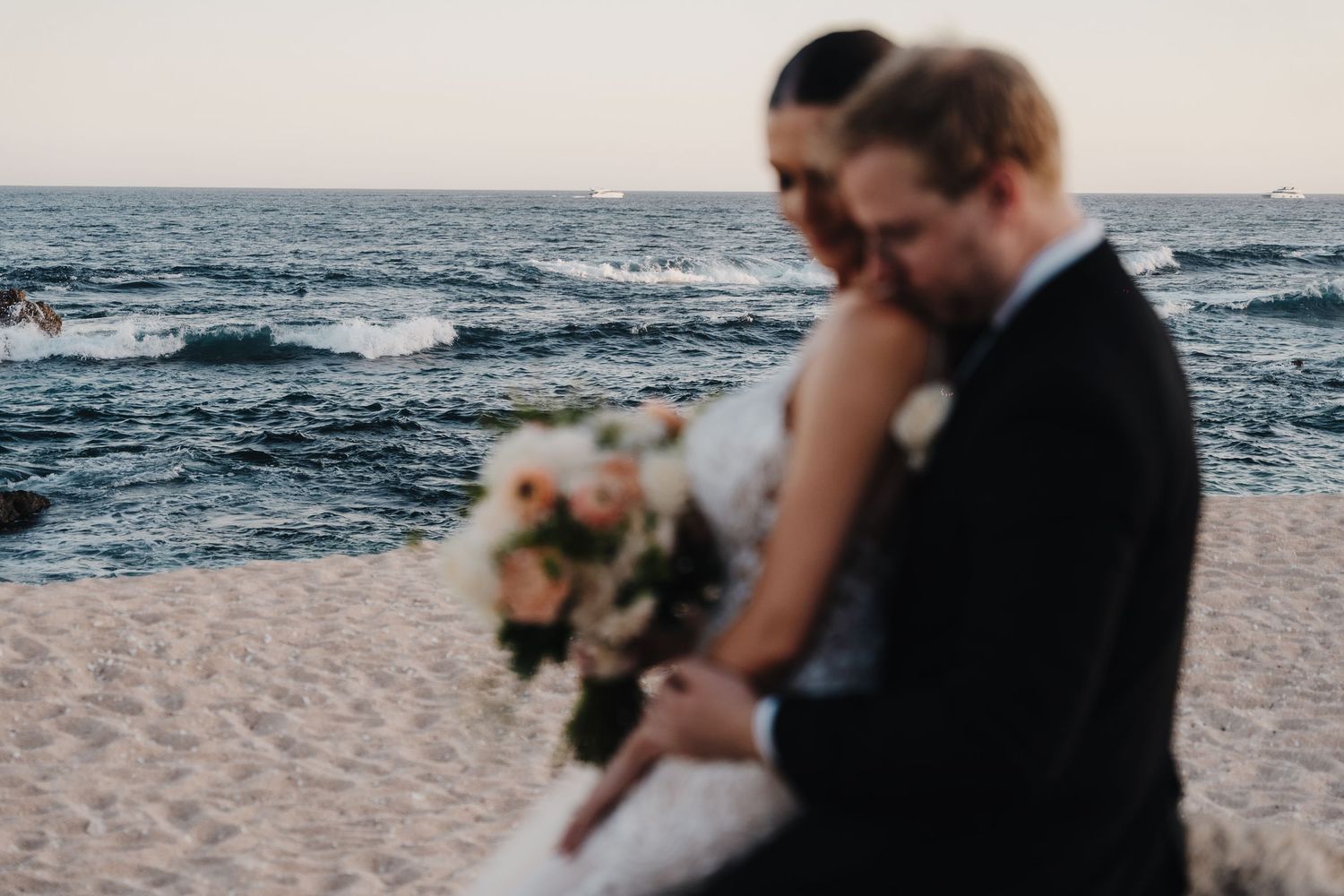 A couple shares an intimate moment on a beach at sunset.