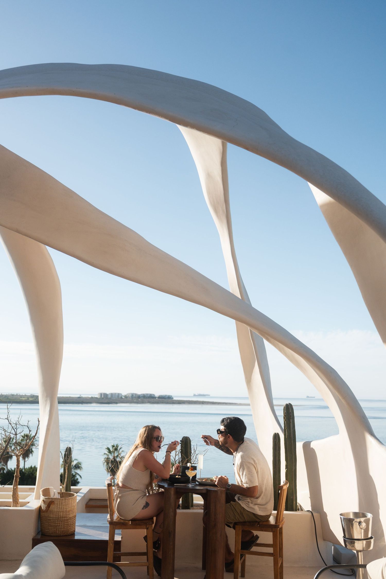 Modern white architectural structure overlooking ocean with curved design elements.