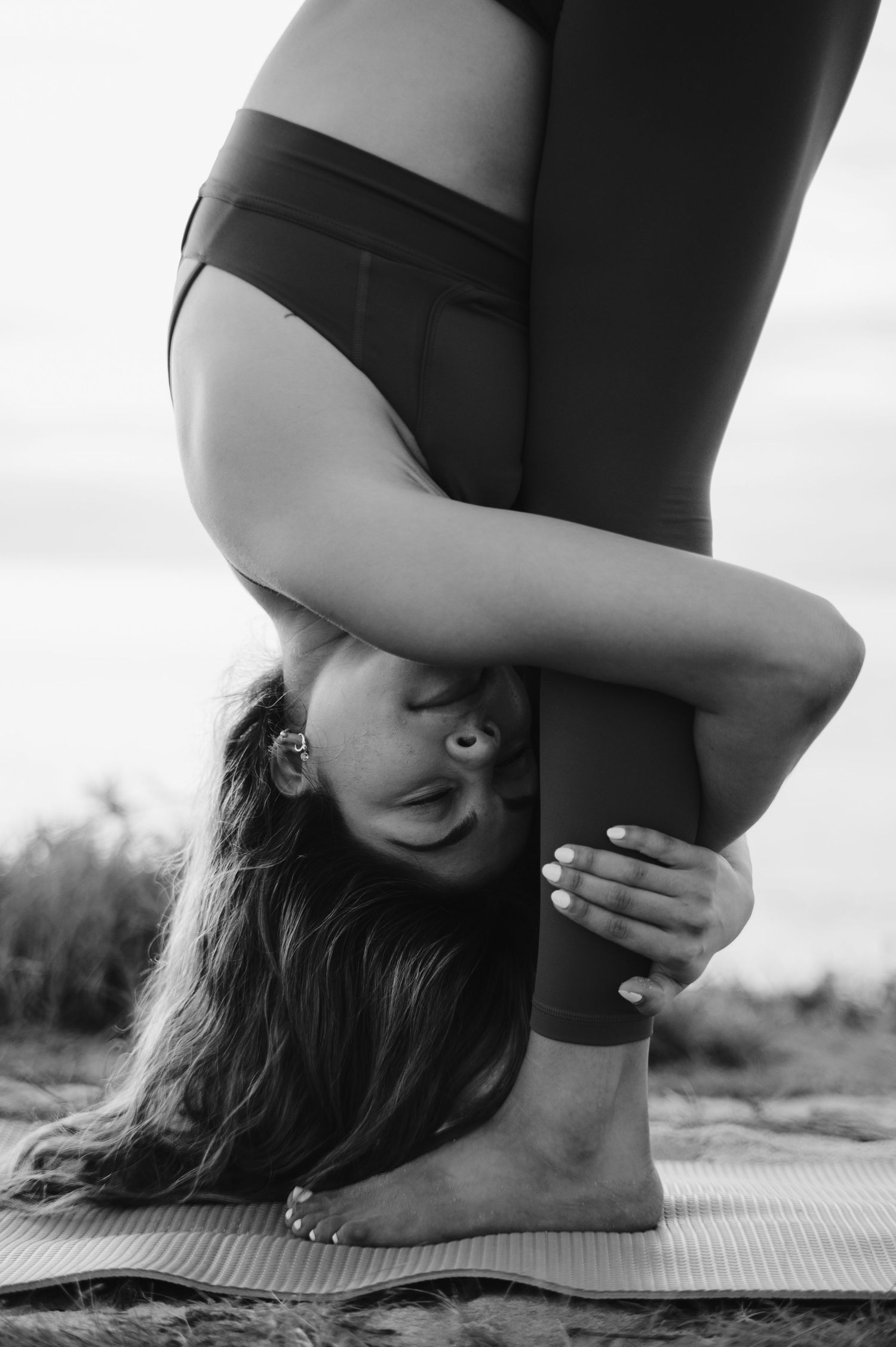 Black and white photo of a yoga pose showing flexibility with long hair flowing down.