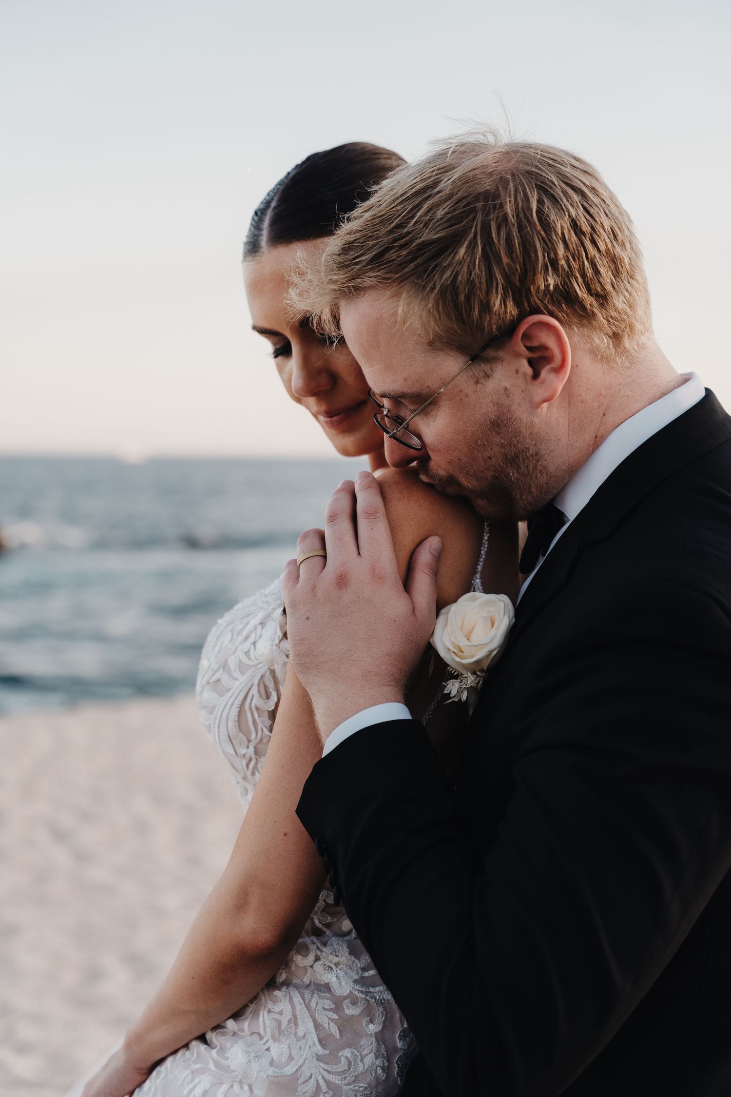 Romantic couple shares an intimate moment on a beach at sunset.
