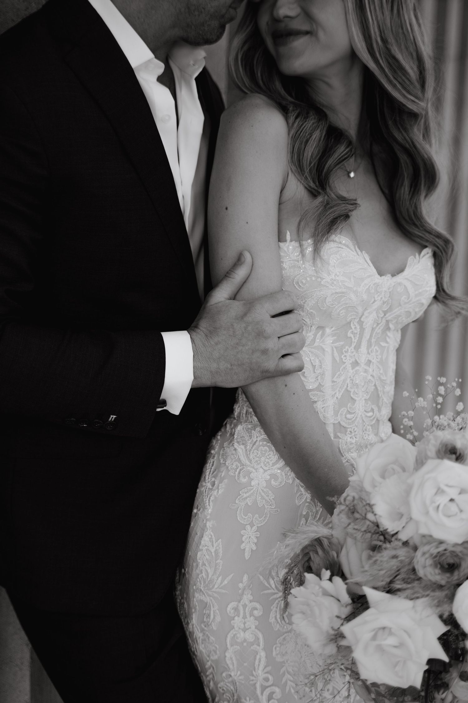 Intimate black and white portrait showing details of a bridal gown and formal attire.