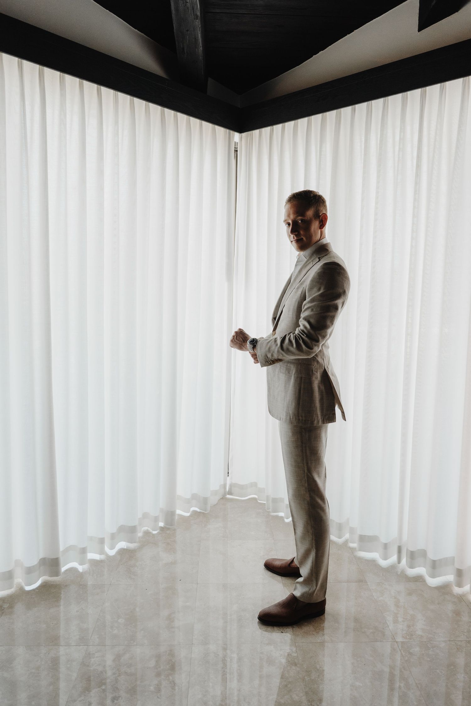 Man in gray suit stands solo in minimalist white room interior.