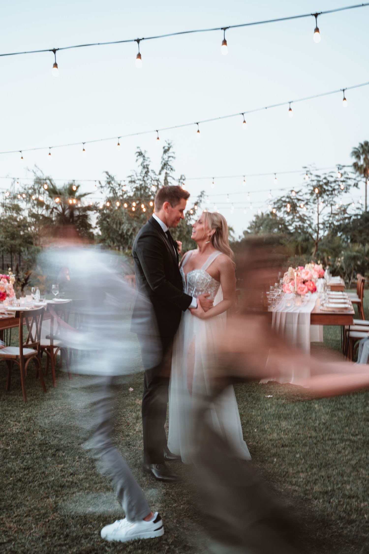 A sequence of motion-blurred photos showing a couple dancing under string lights in an outdoor setting.