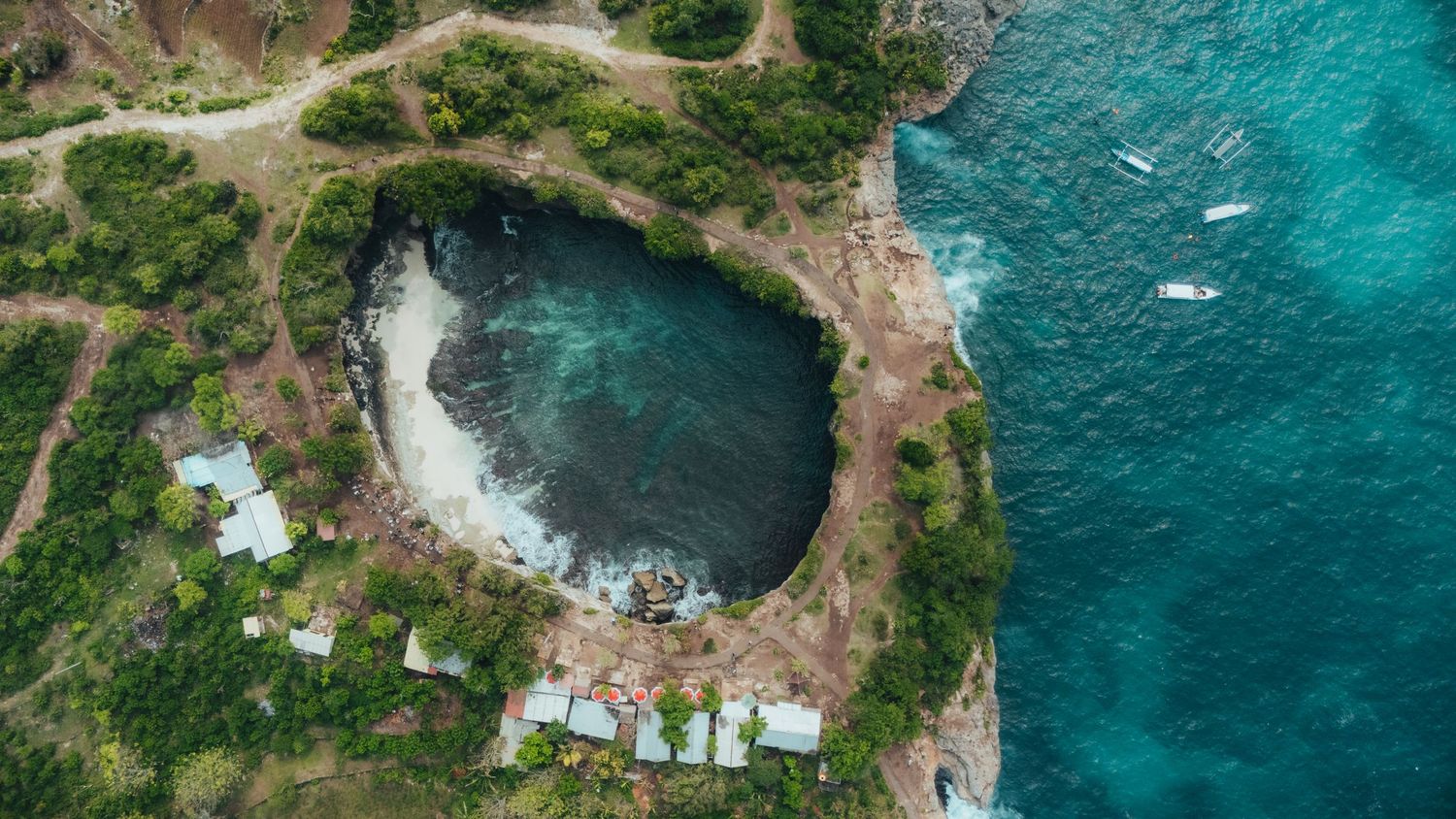 Dramatic aerial view of a tropical coastline with rugged cliffs and vibrant blue ocean waters.