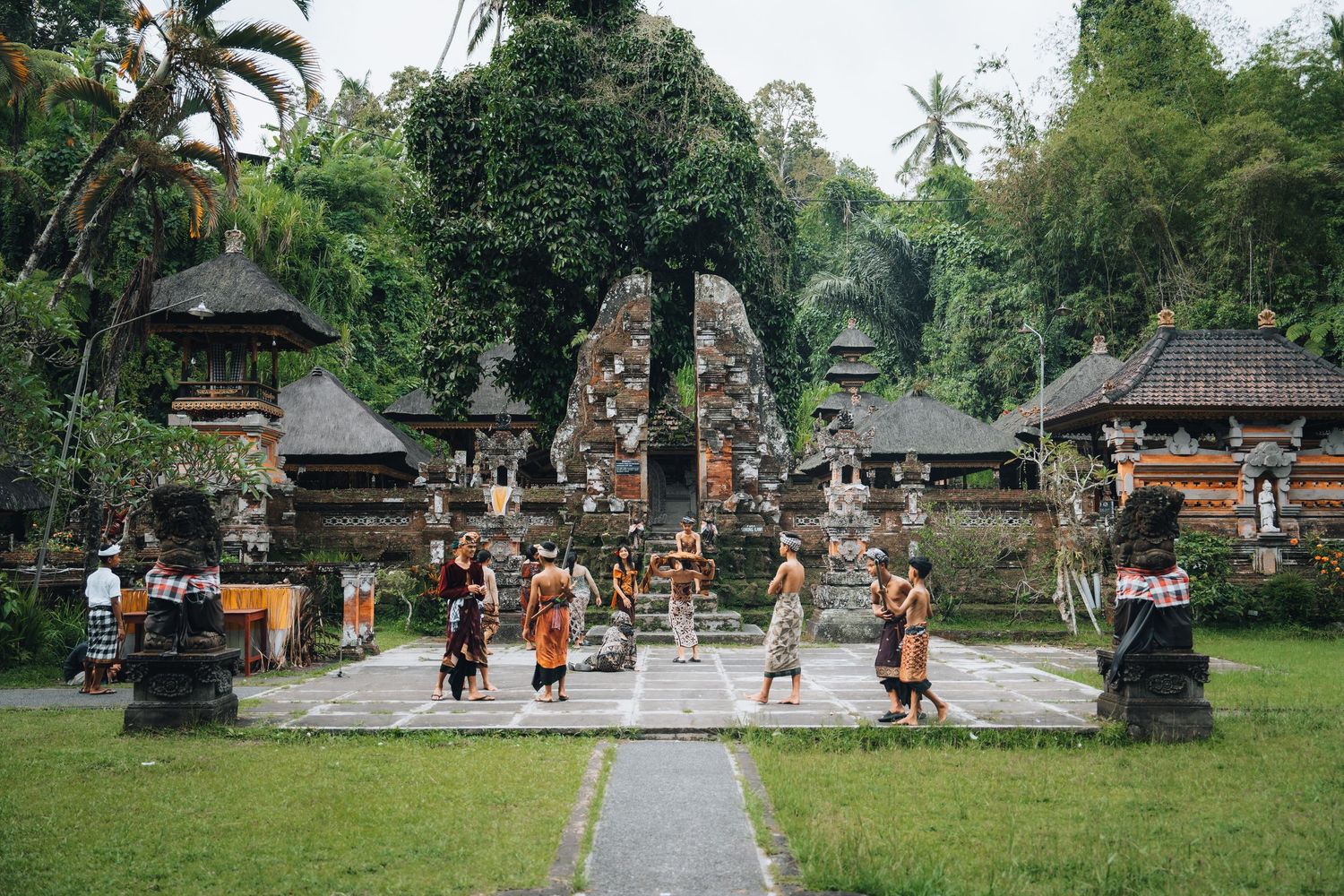 Traditional Balinese temple gates and pathways with palm trees in a lush garden setting.
