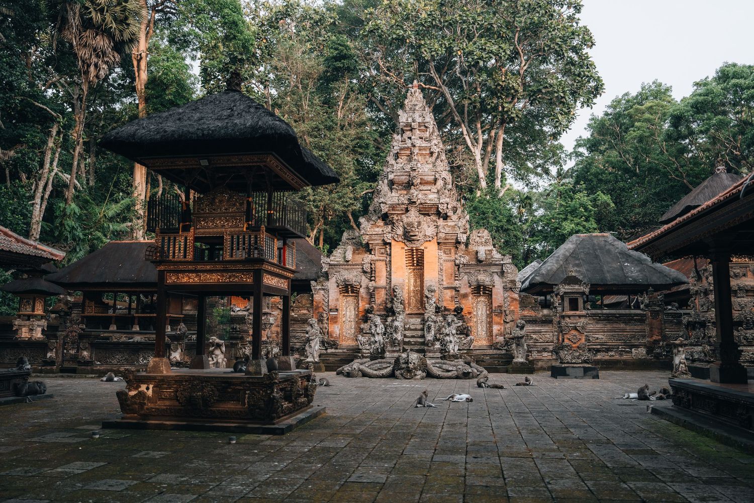 Traditional Balinese temple complex surrounded by trees at sunset.