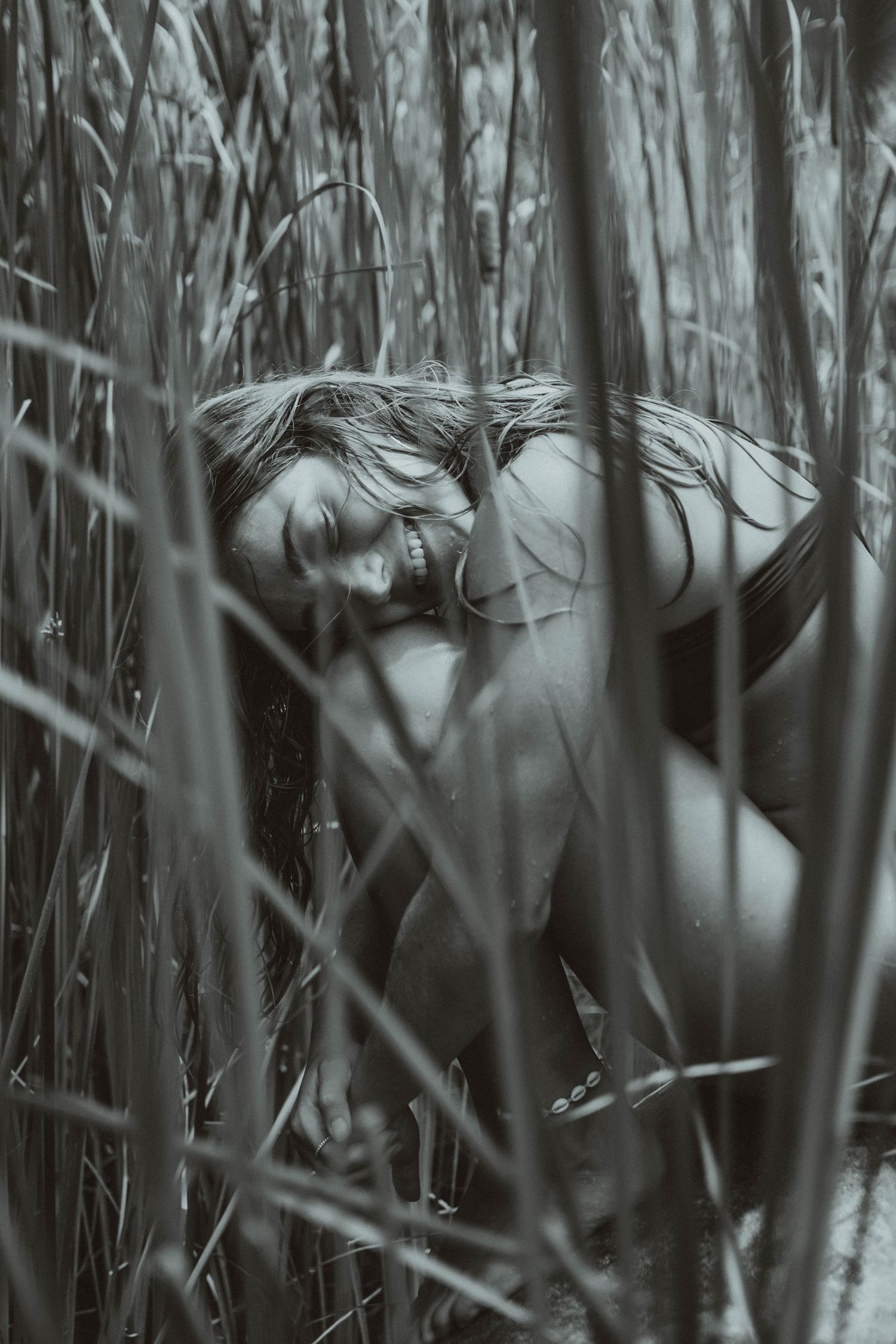 Moody black and white portrait through tall reeds and grass.