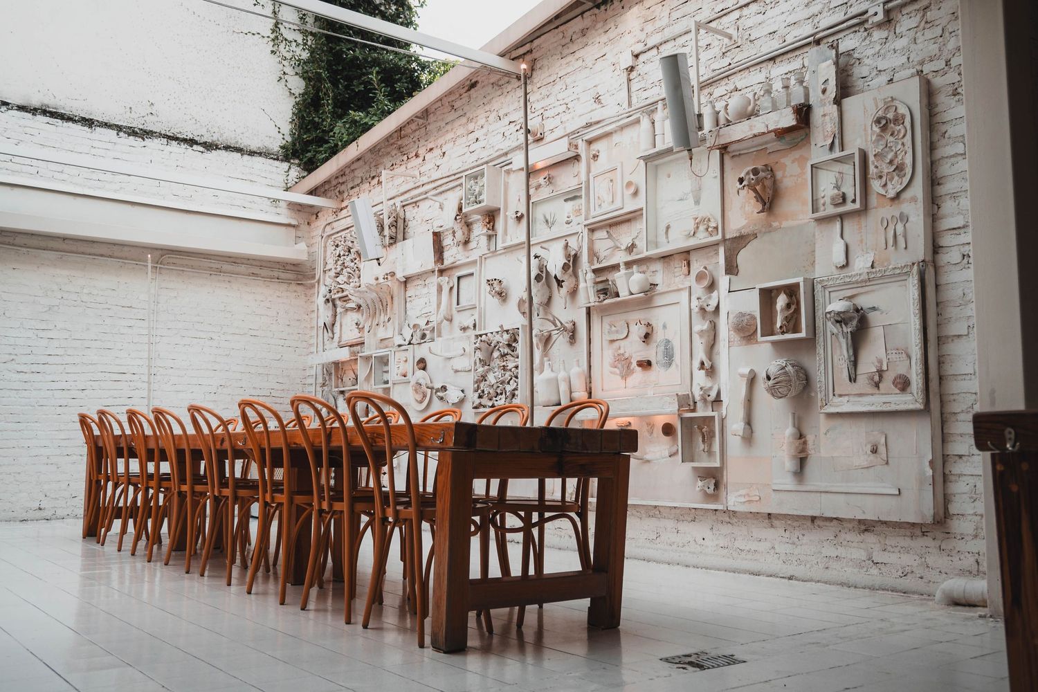 Rustic dining room with wooden chairs and artistic wall display featuring vintage white frames.