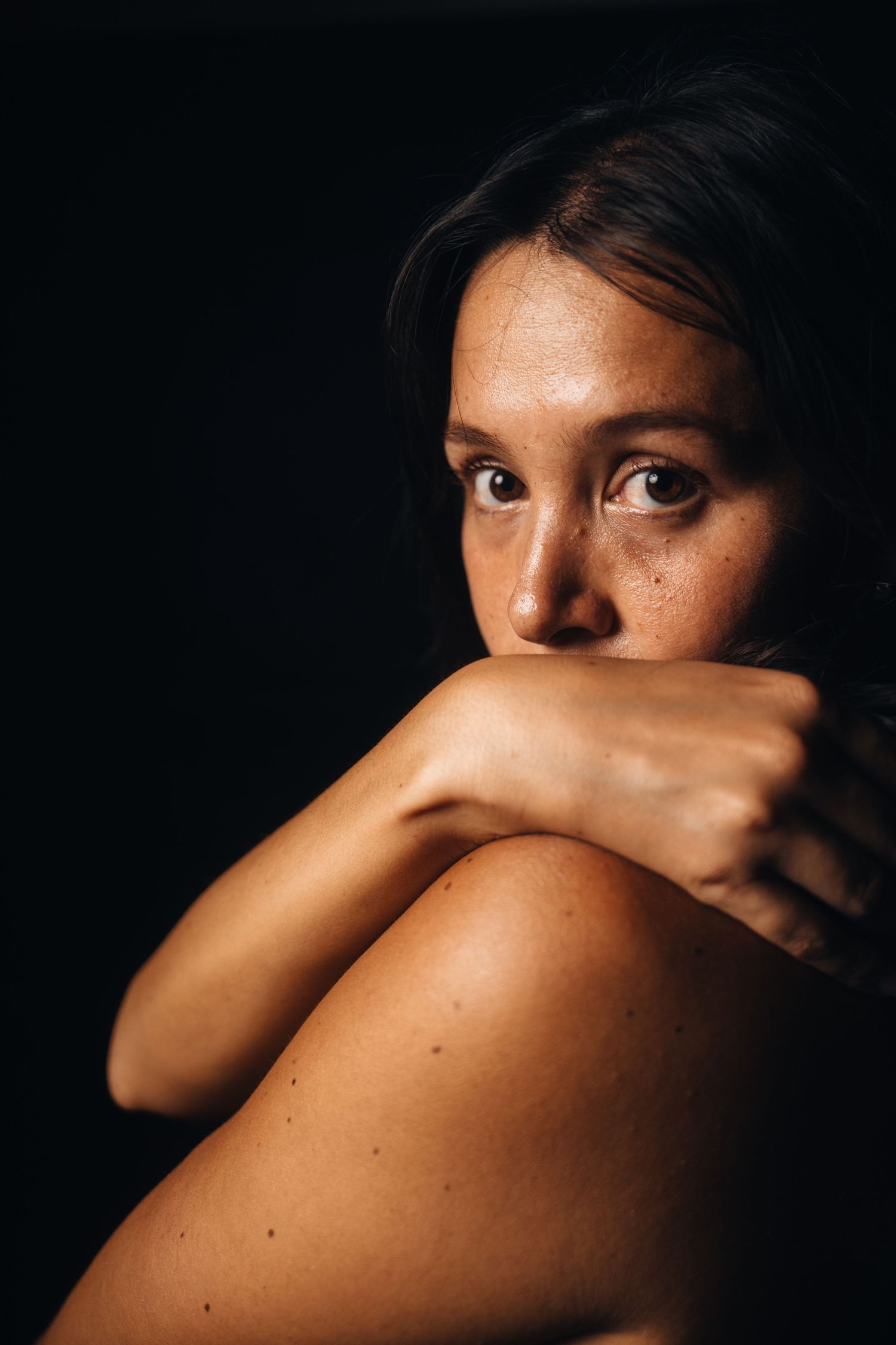 Intimate portrait photograph with soft lighting against dark background.
