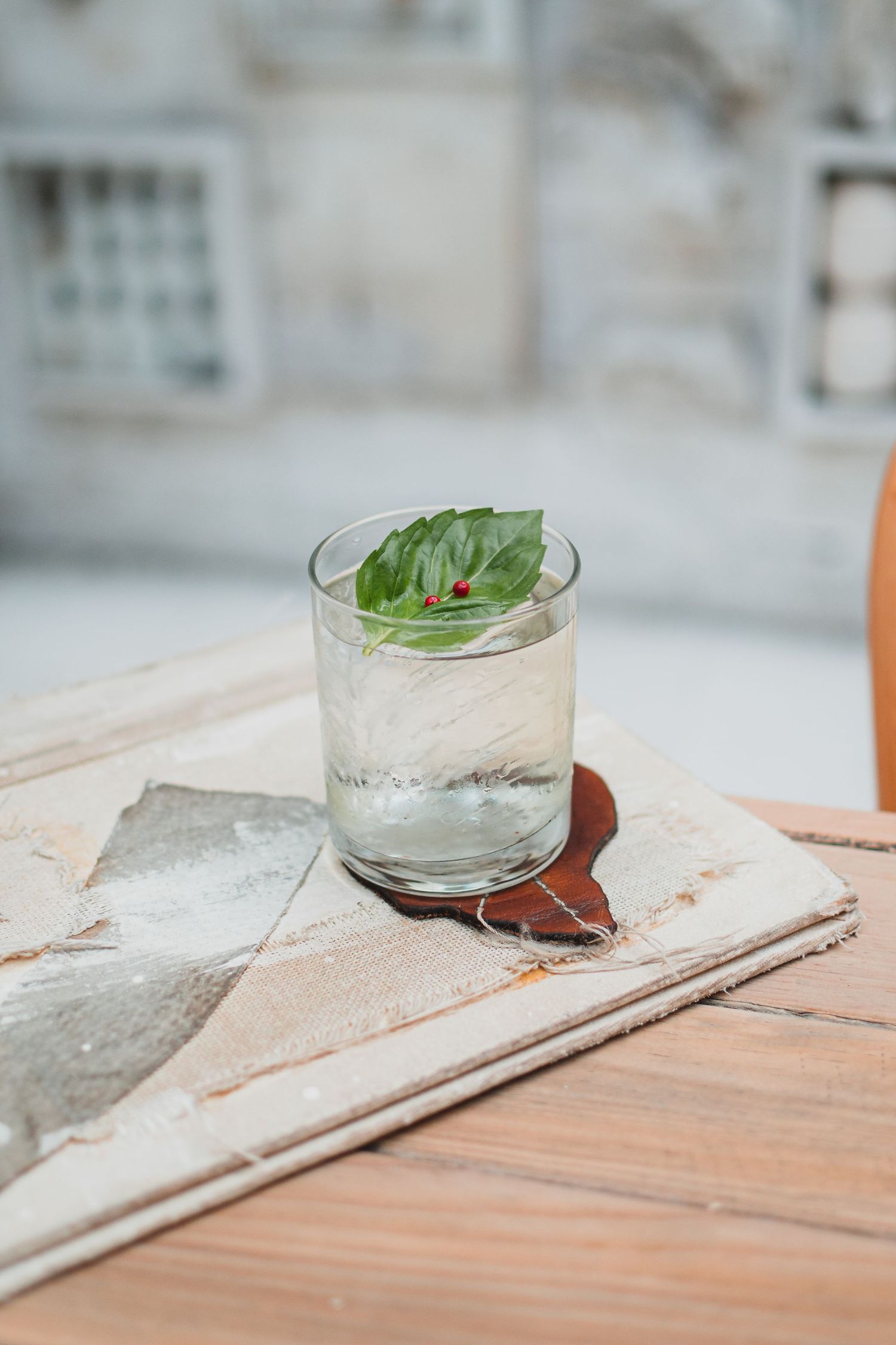 Glass cups with fresh herbs and ingredients on a wooden table surface.