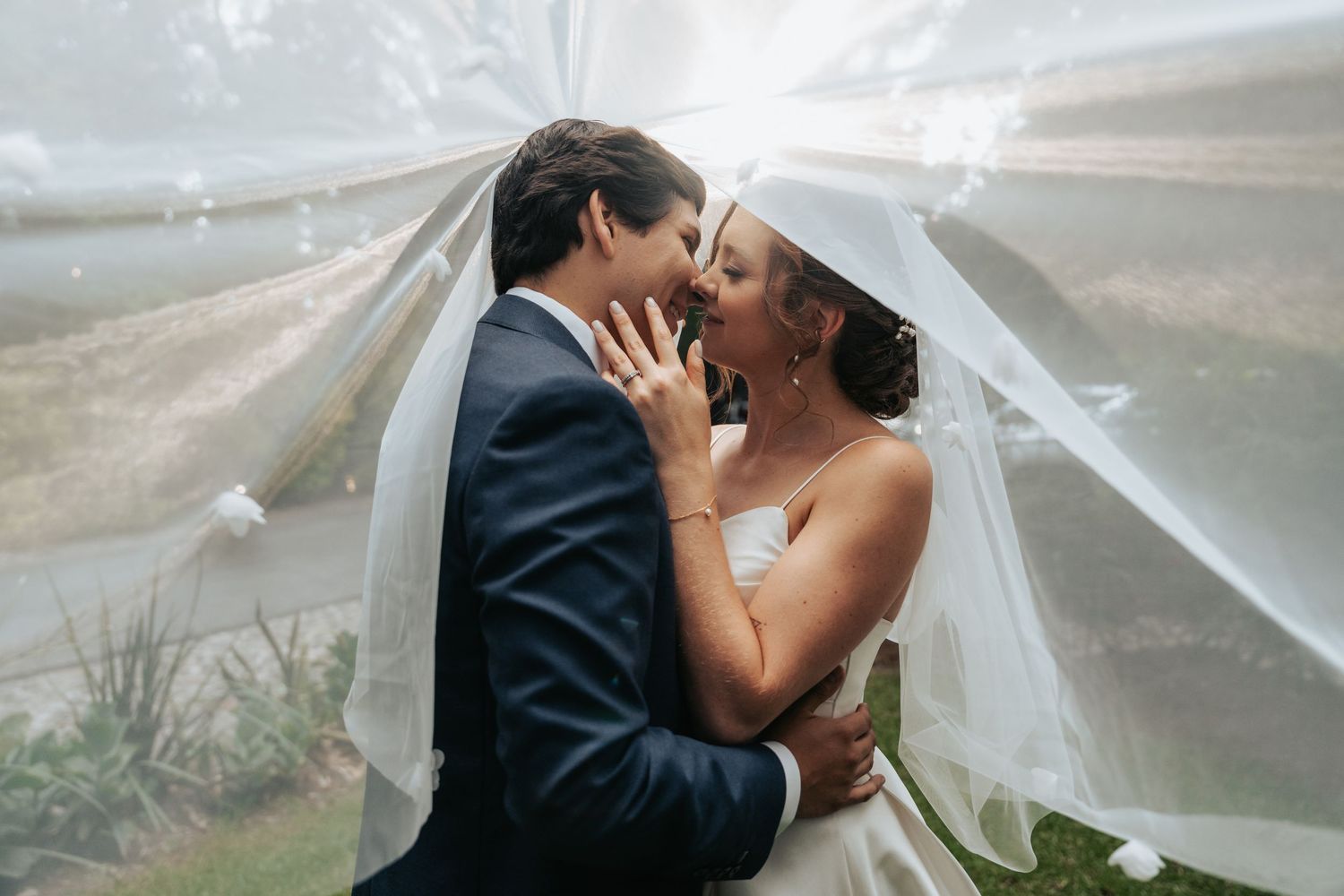 Intimate wedding photography with flowing white veil against natural landscape.