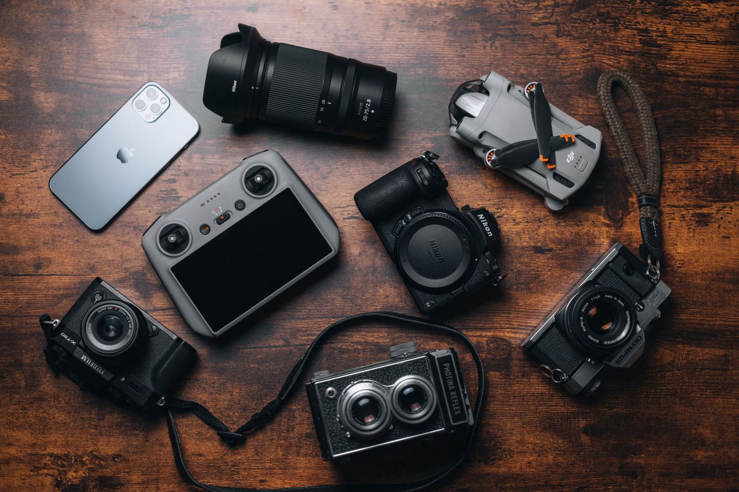 Collection of vintage and modern cameras and photography equipment on wooden surface.