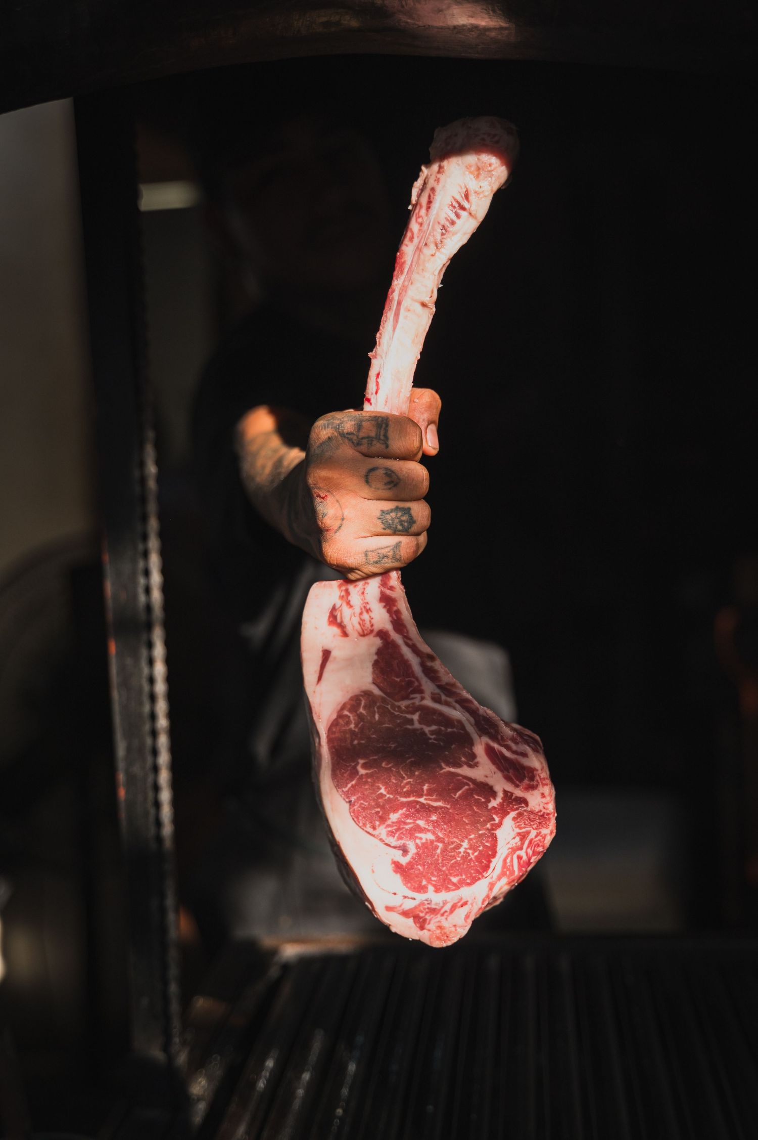 Raw ribeye steaks suspended in dramatic lighting against a dark background.