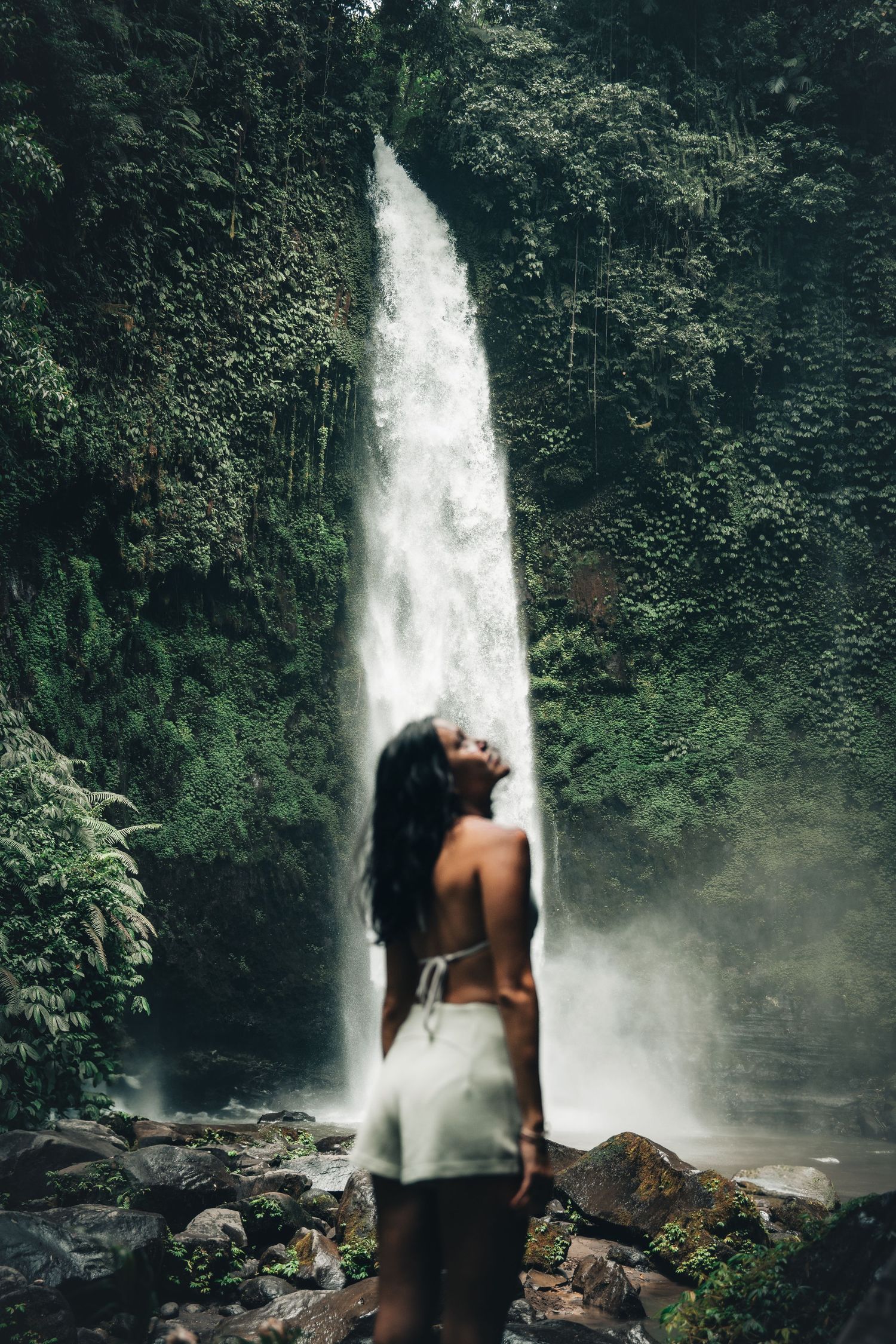 Majestic waterfall cascading down tropical cliffs surrounded by lush greenery.