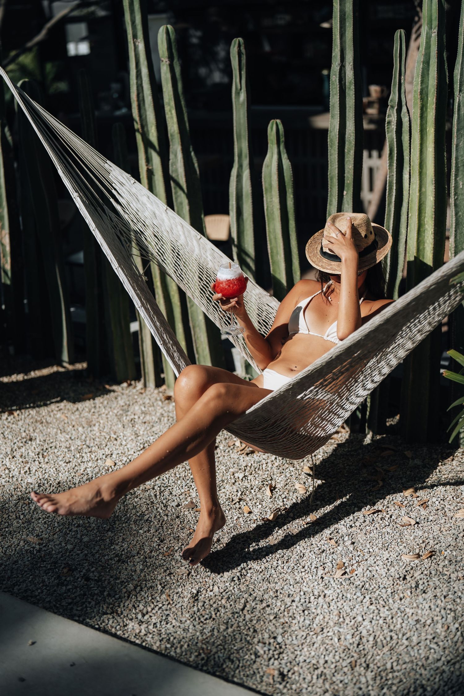 Relaxing in white hammock surrounded by tall bamboo plants in tropical setting.