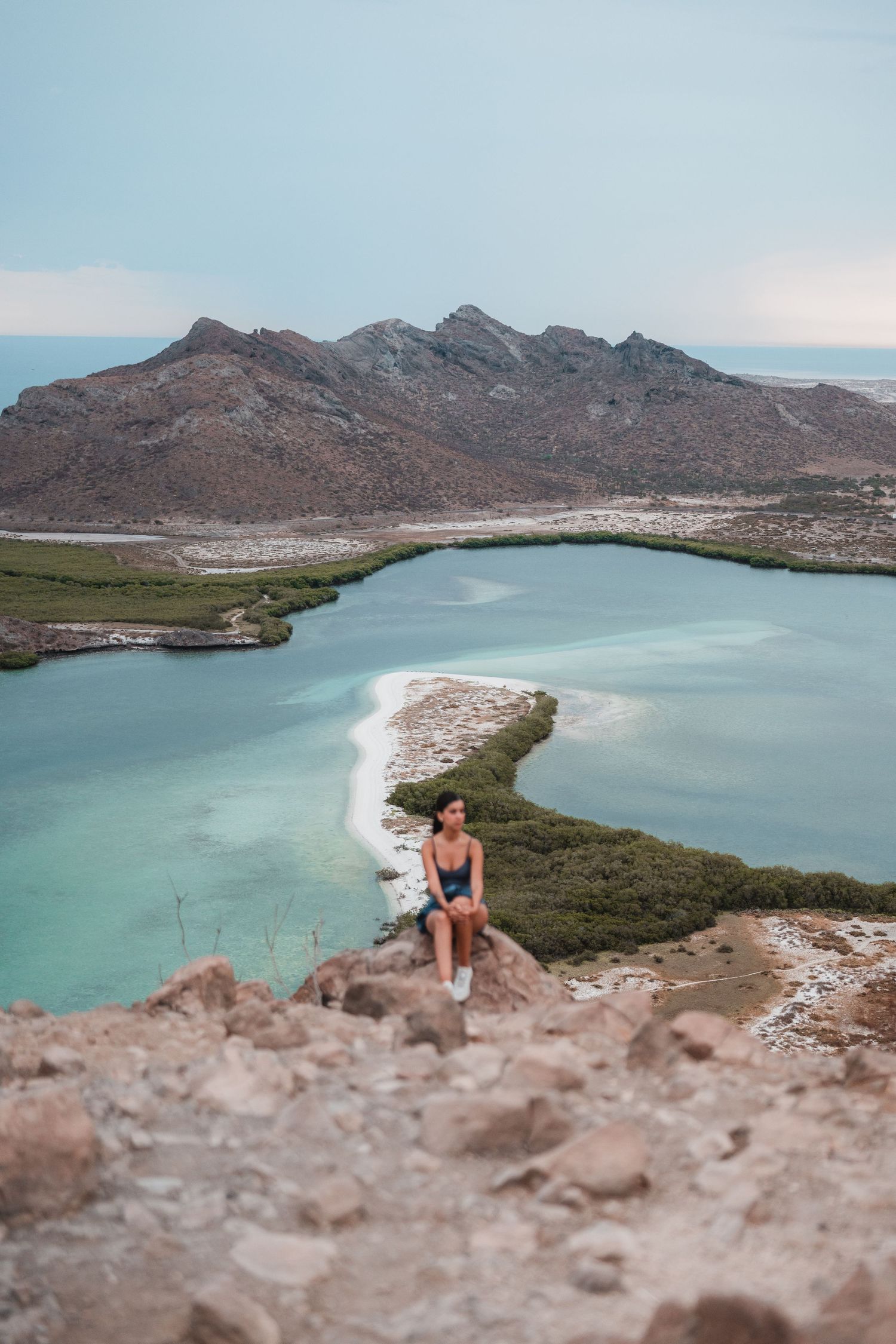 Aerial view of curved coastline with turquoise waters and rocky mountains.