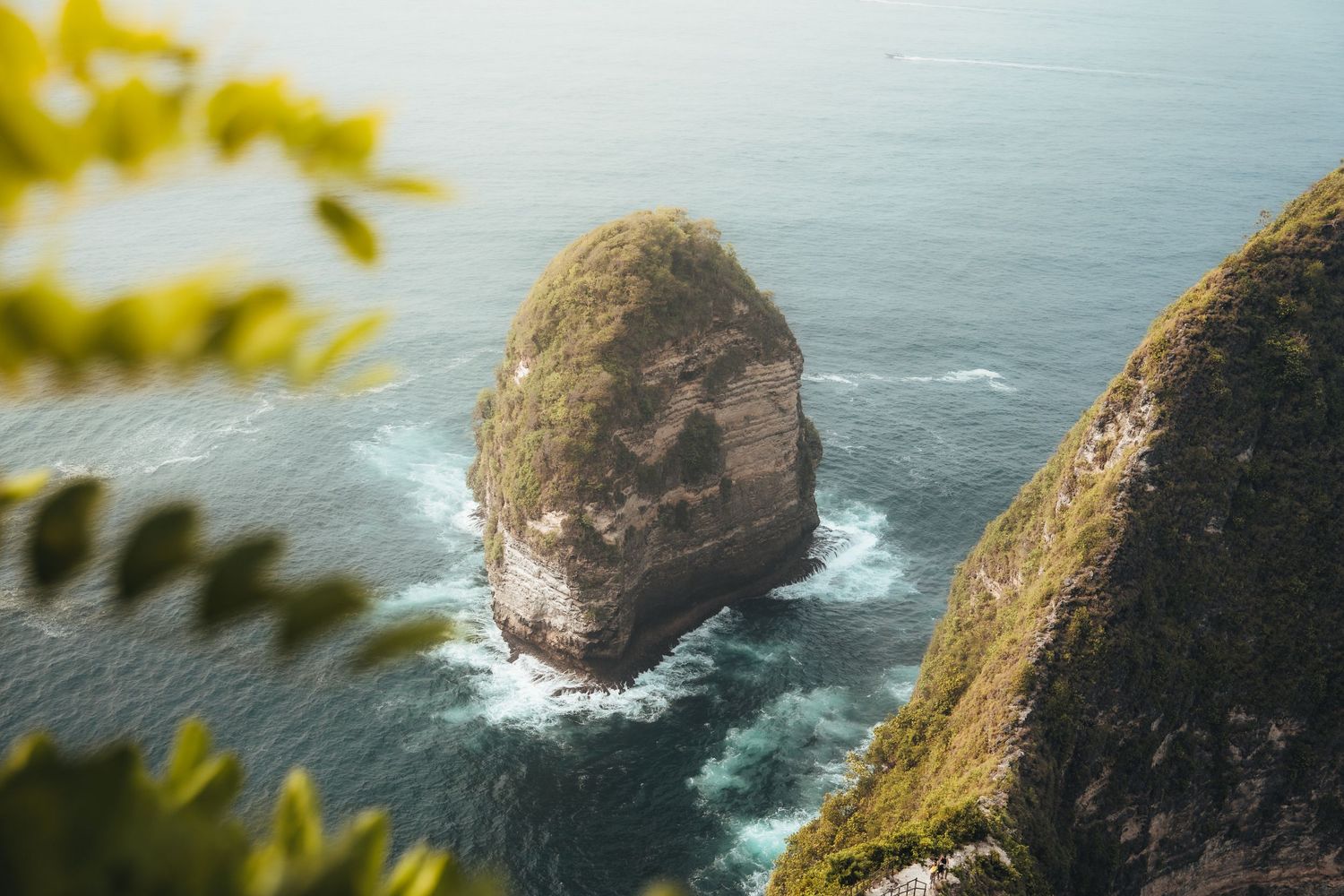Turquoise waters surrounding dramatic coastal cliffs at Kelingking Beach viewpoint.