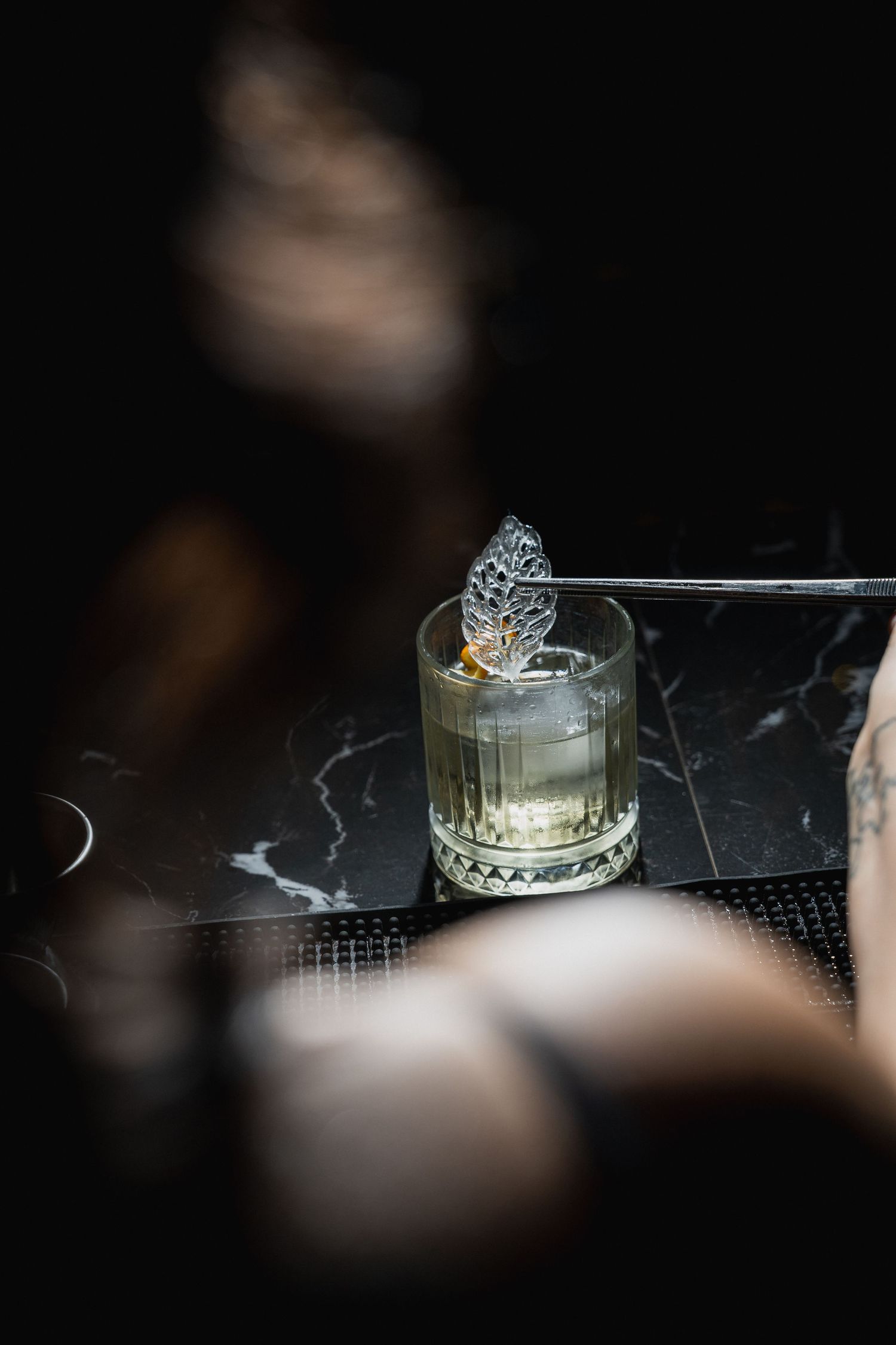 Elegant crystal glassware arranged on a dark marble surface in moody lighting.