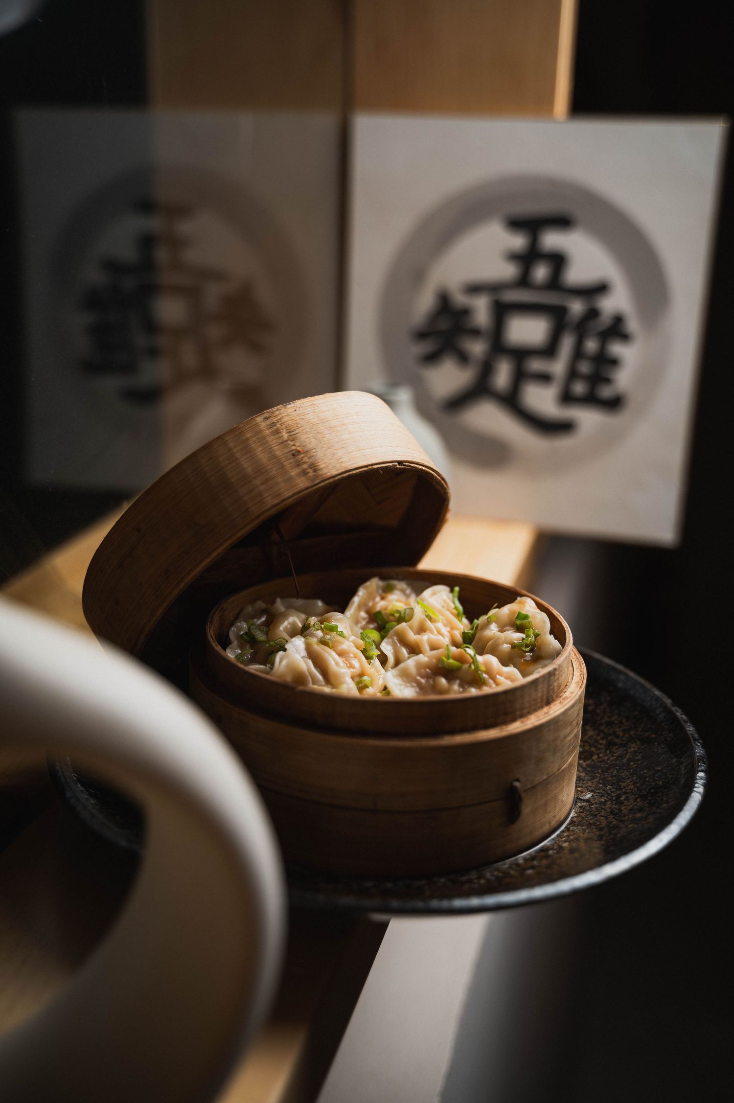 Traditional bamboo steamer basket with dim sum dumplings in moody lighting.