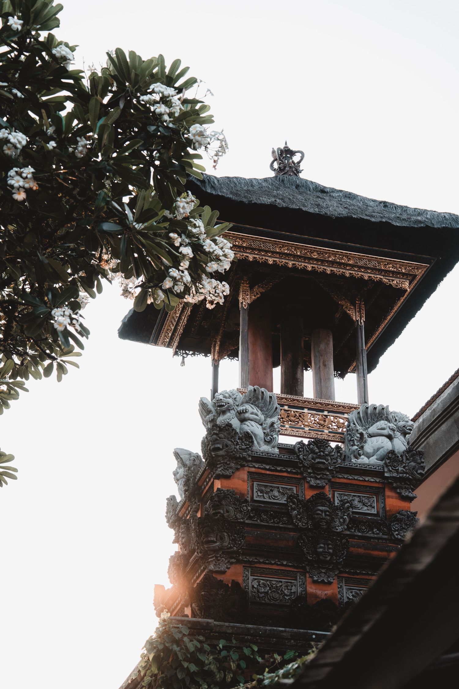 Traditional Balinese temple architecture with ornate roof details and decorative carvings at sunset.