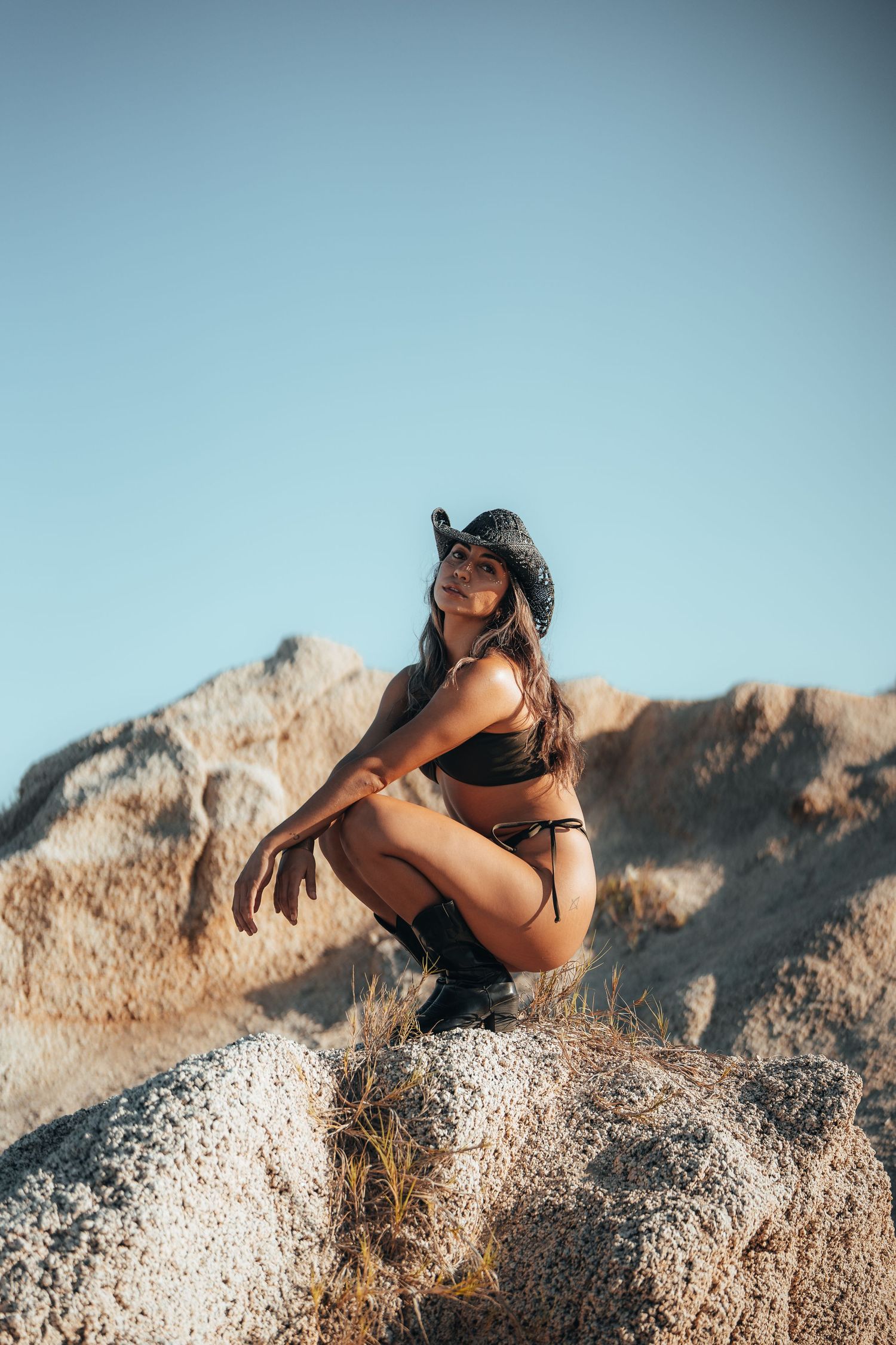 Athletic pose on rocky terrain against bright blue sky.