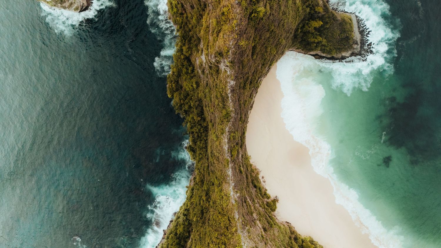 Aerial view of rugged coastal cliffs with turquoise waters crashing against the rocks.