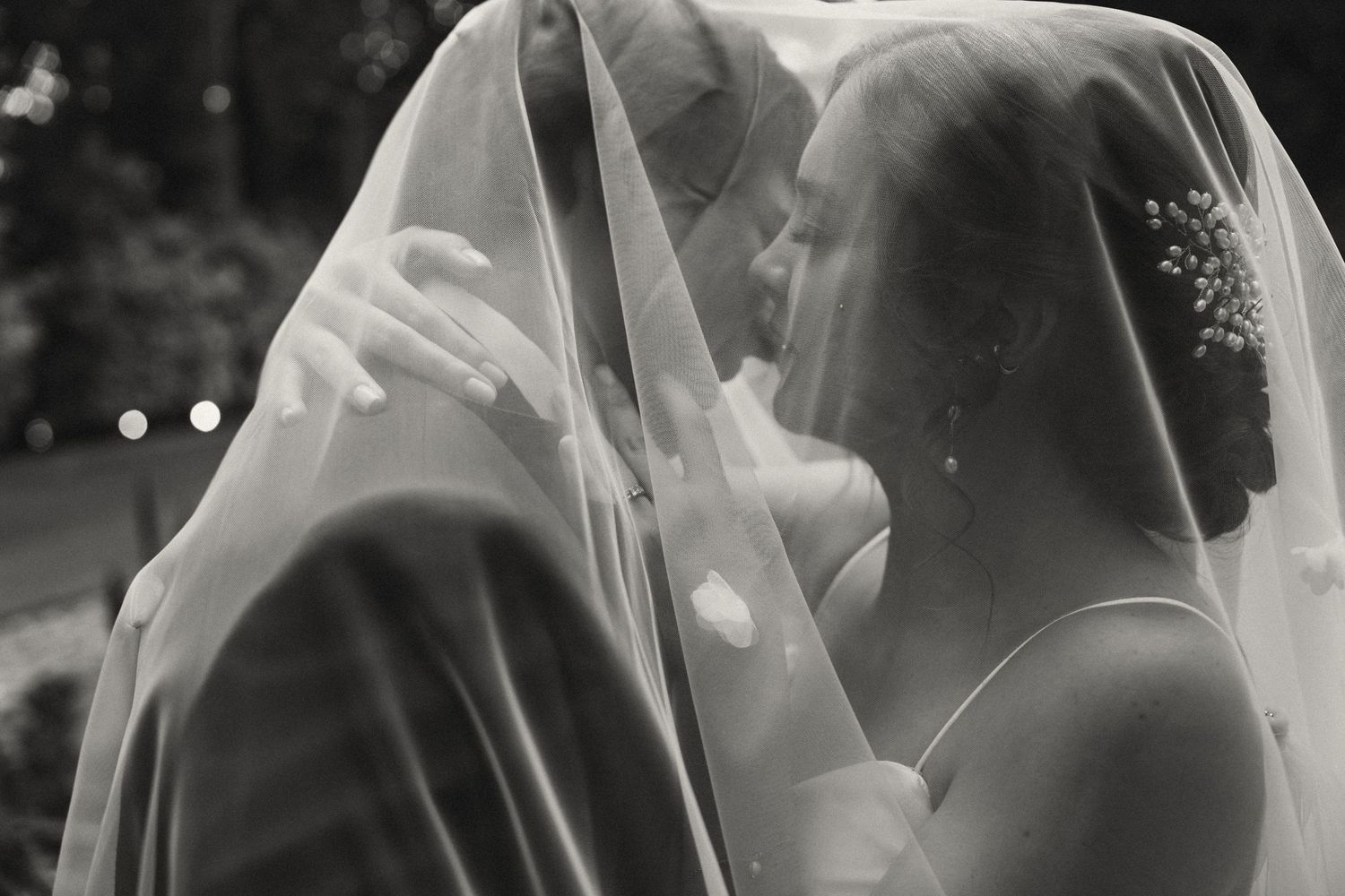 Romantic black and white detail of a veiled couple sharing an intimate moment.