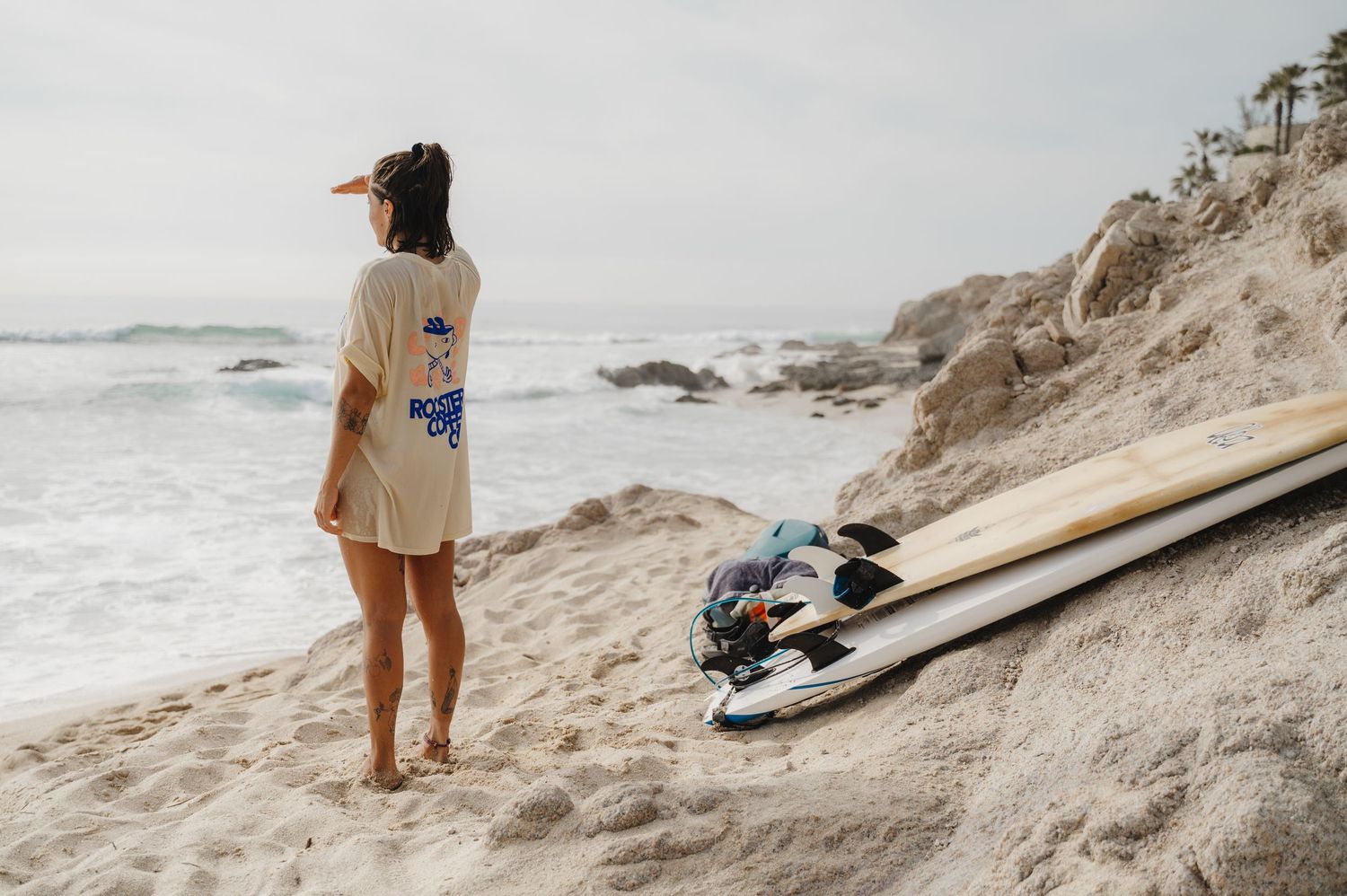 Surfboards and beach gear arranged on sandy coastal slope.