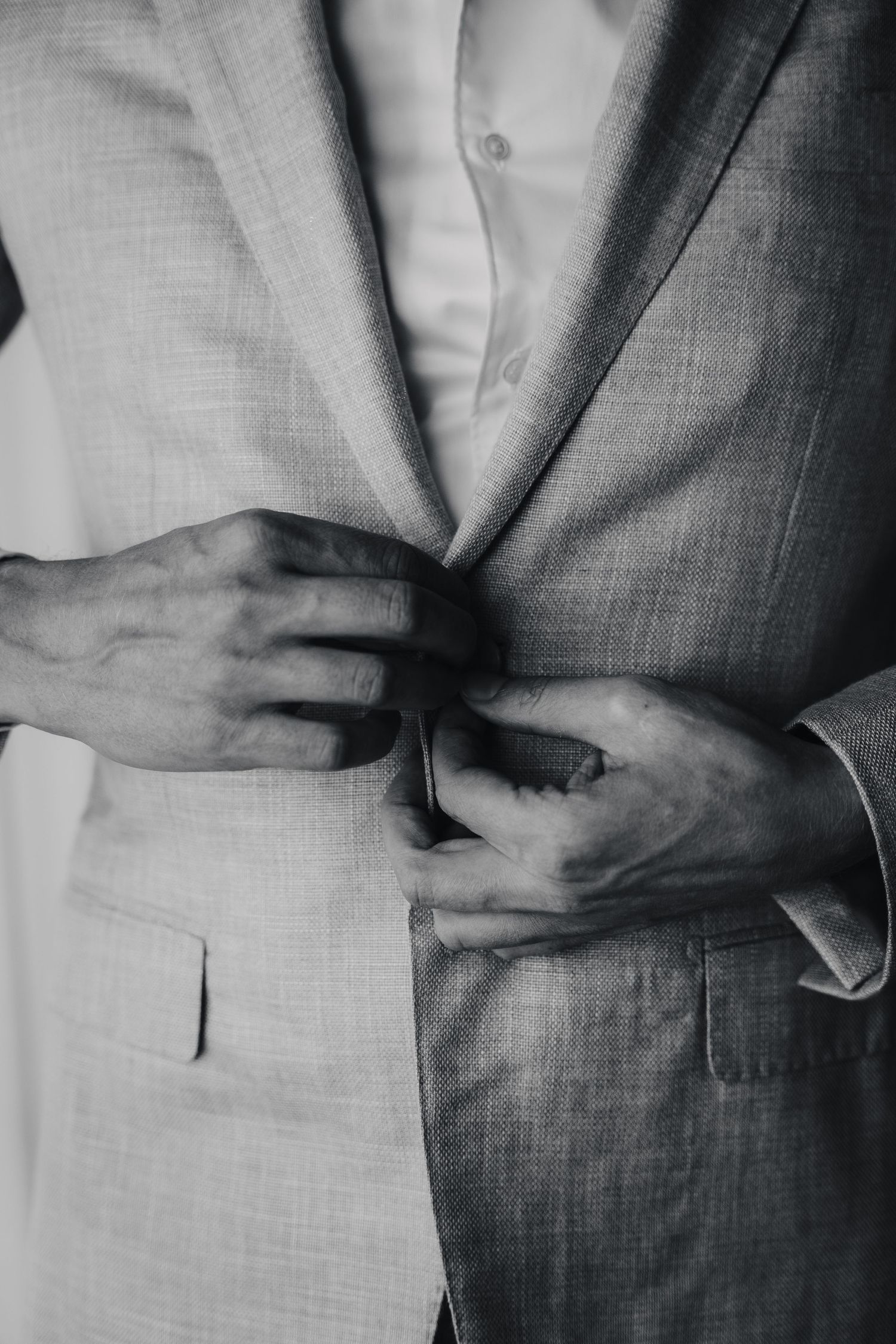 Close-up details of light grey textured suit fabric and jacket buttons.
