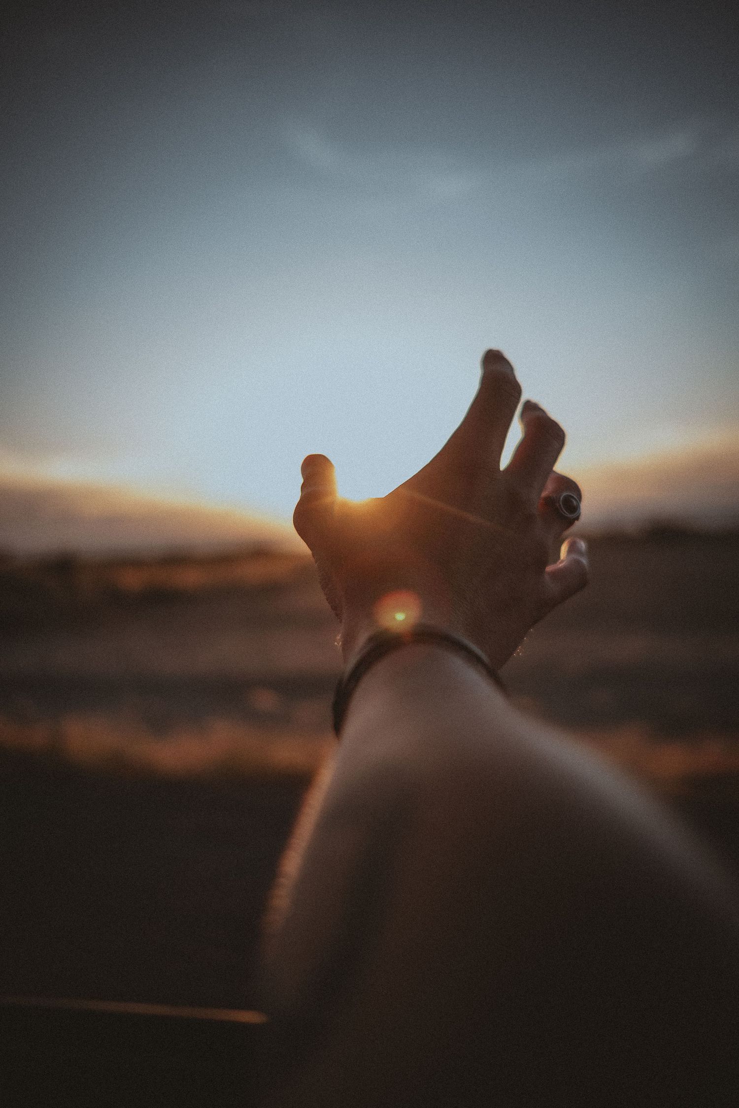 Feet silhouetted against a sunset sky with mountains in the background.
