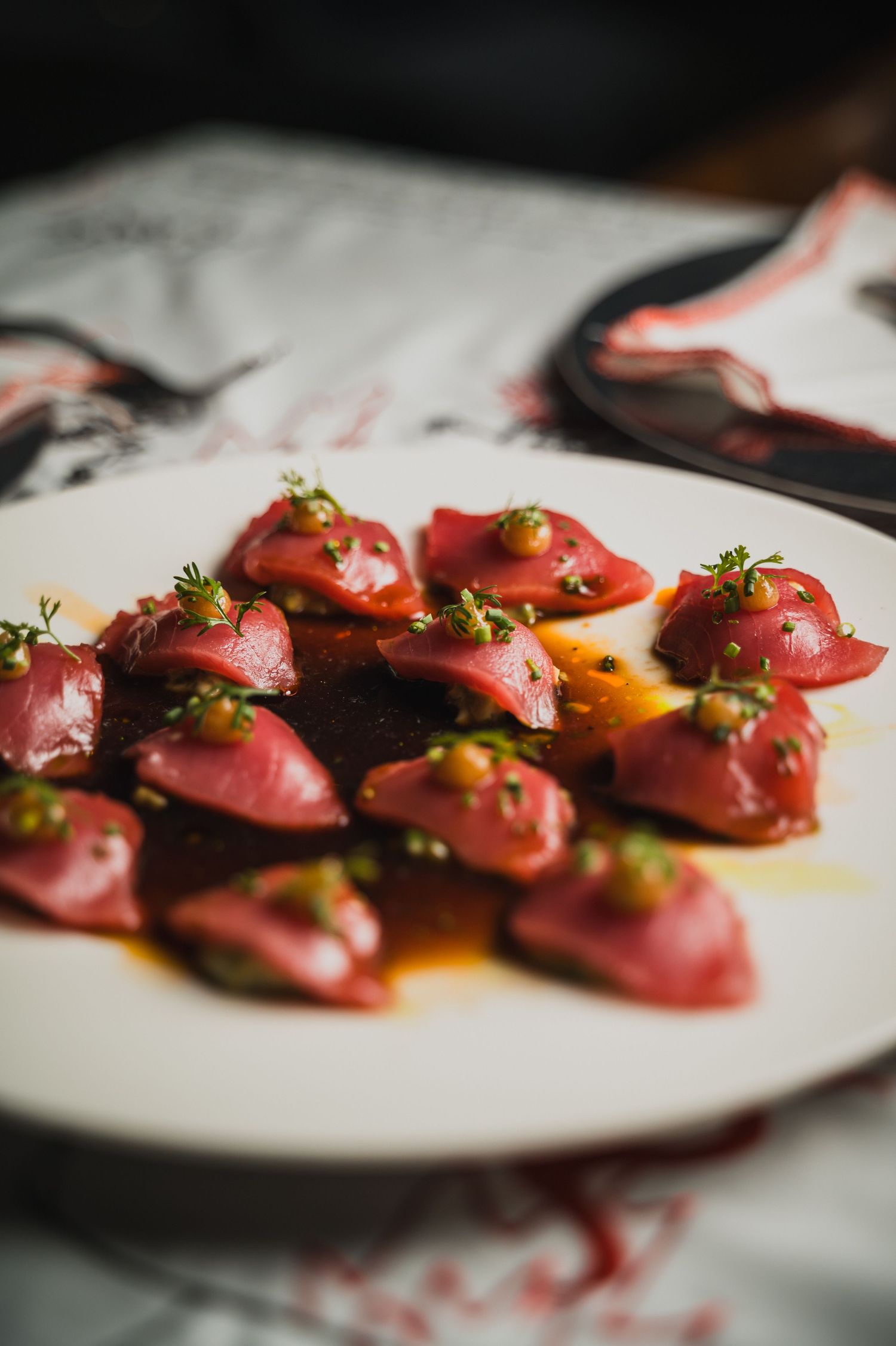 Beautifully plated raw tuna appetizers with microgreens on a white surface.